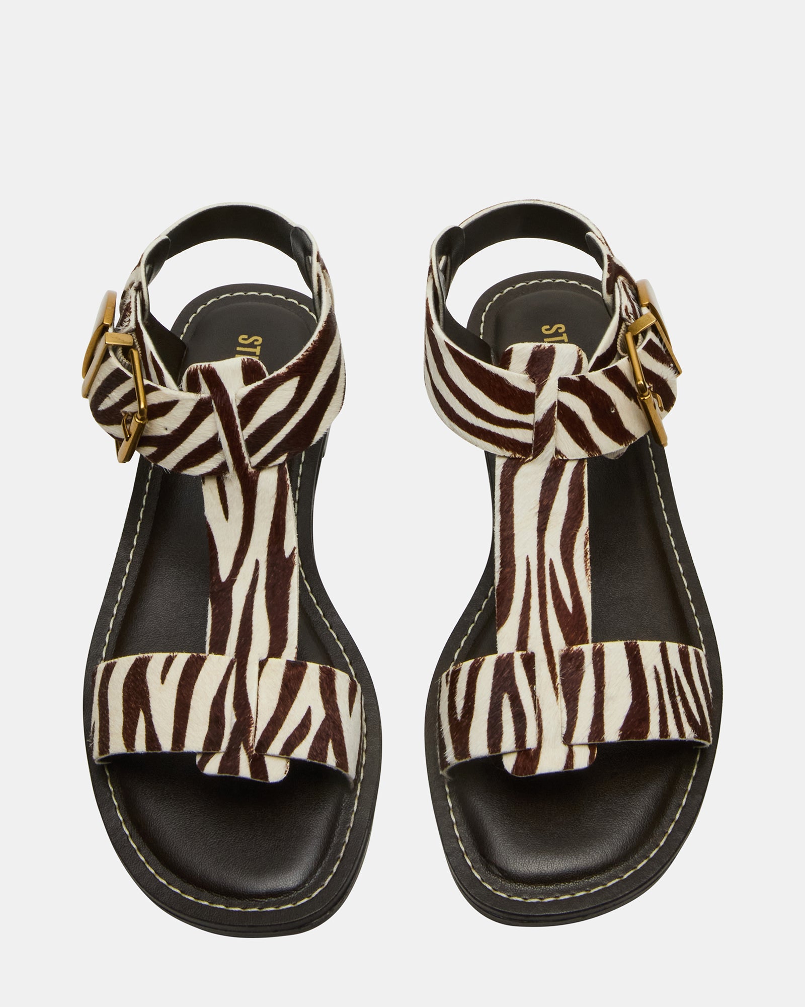 Side view of BRAZINN zebra flat sandals with ankle strap on a summer outdoor setting