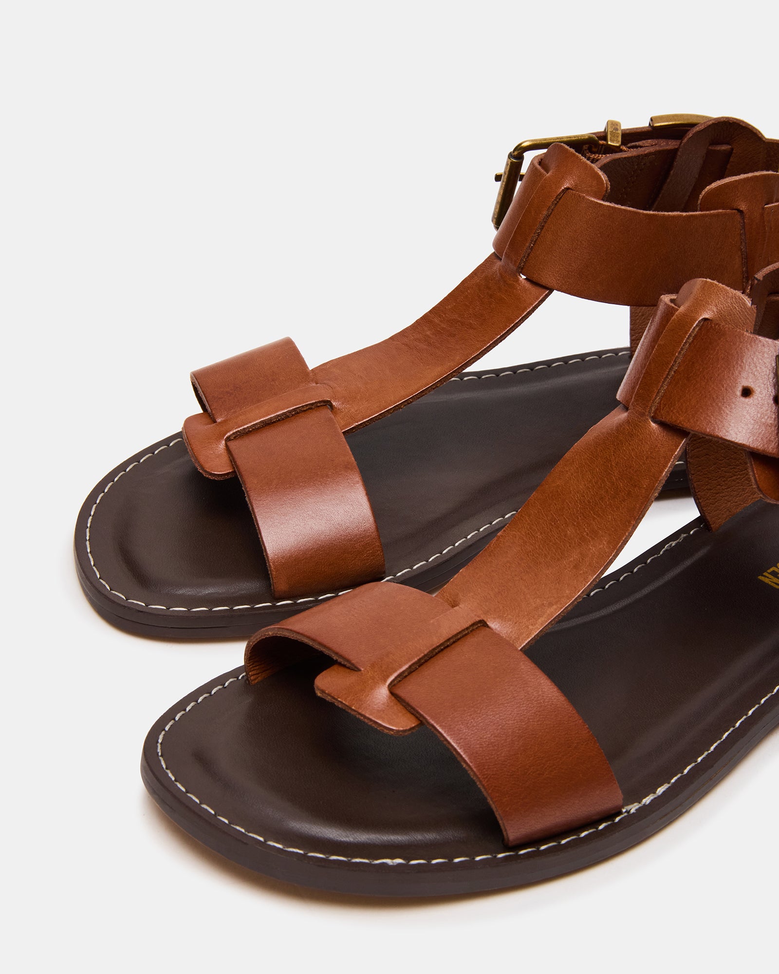 Side view of BRAZINN tan leather flat sandals with ankle strap and stylish straps