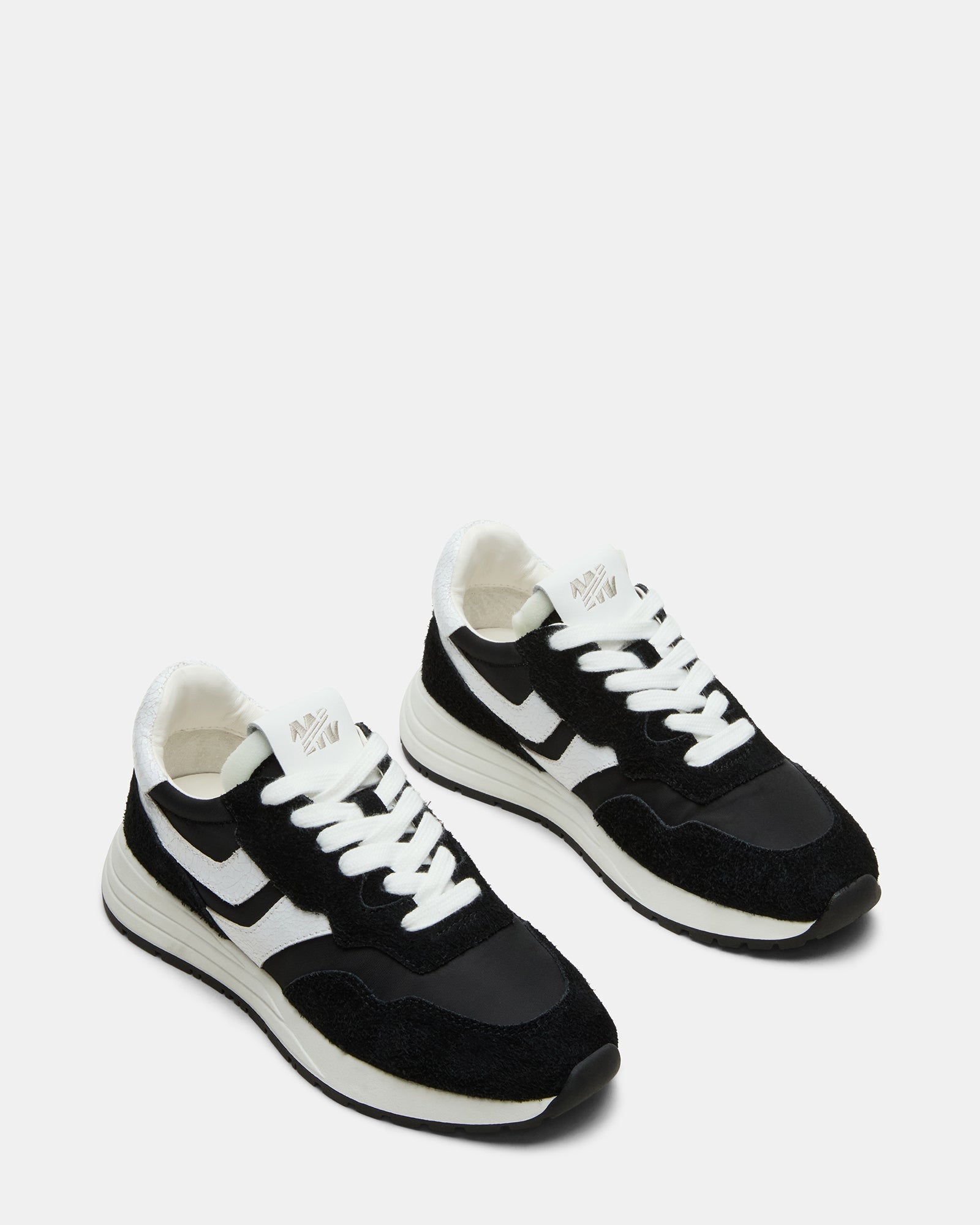 Black and white sneakers displayed on a casual outfit.