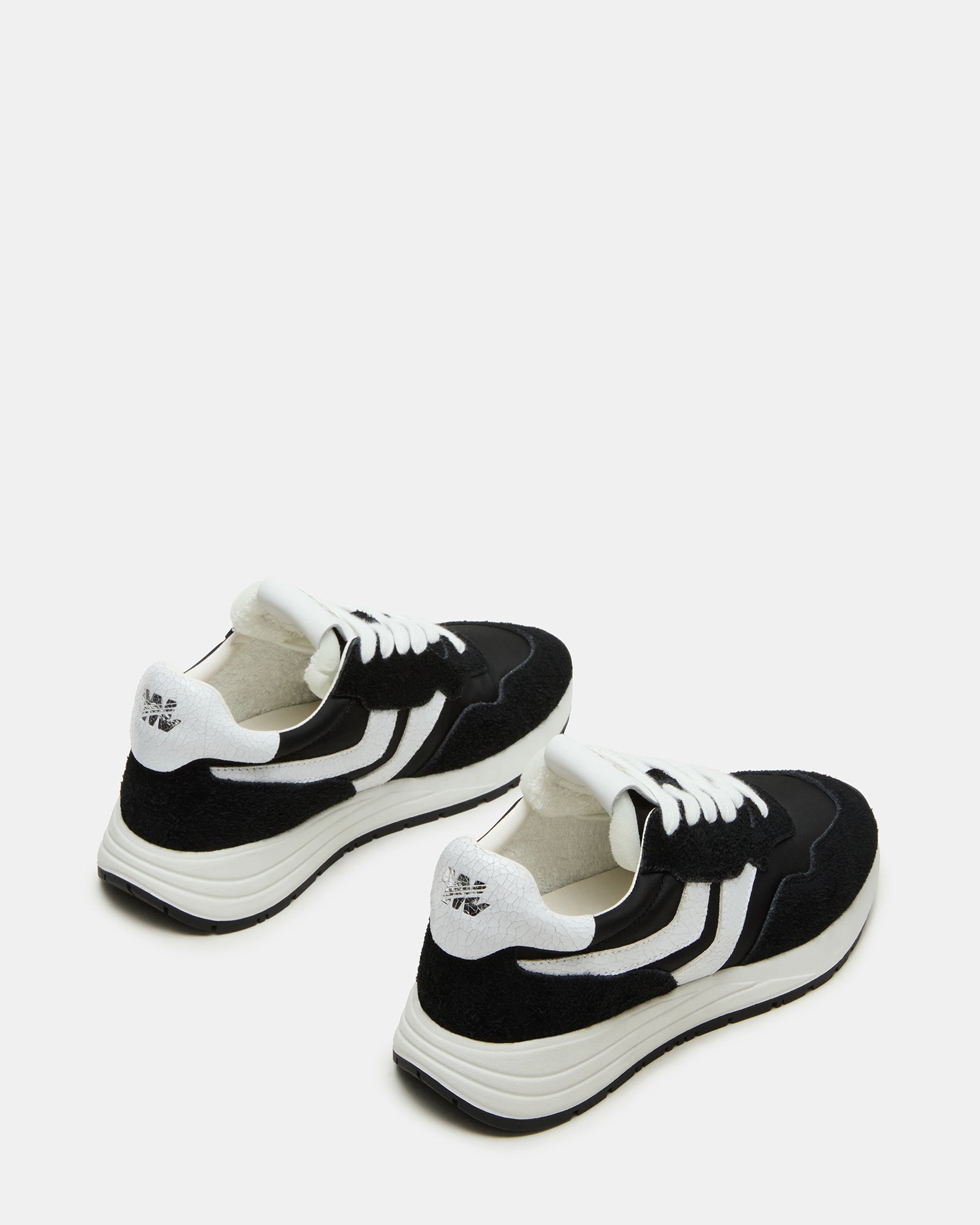 Black and white sneakers displayed on a casual outfit.