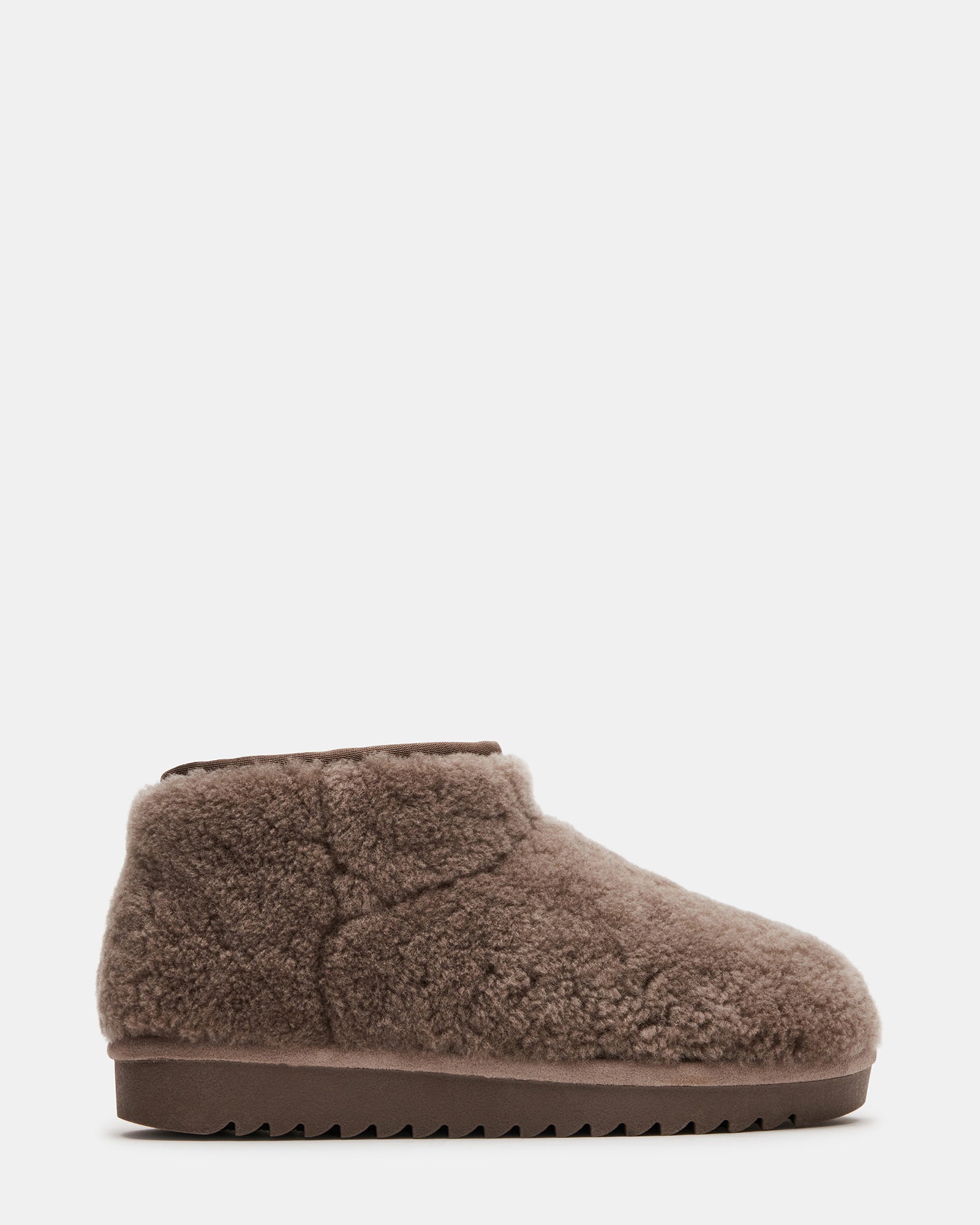 Side view of bootie slippers for women in grey faux shearling on rustic wood floor