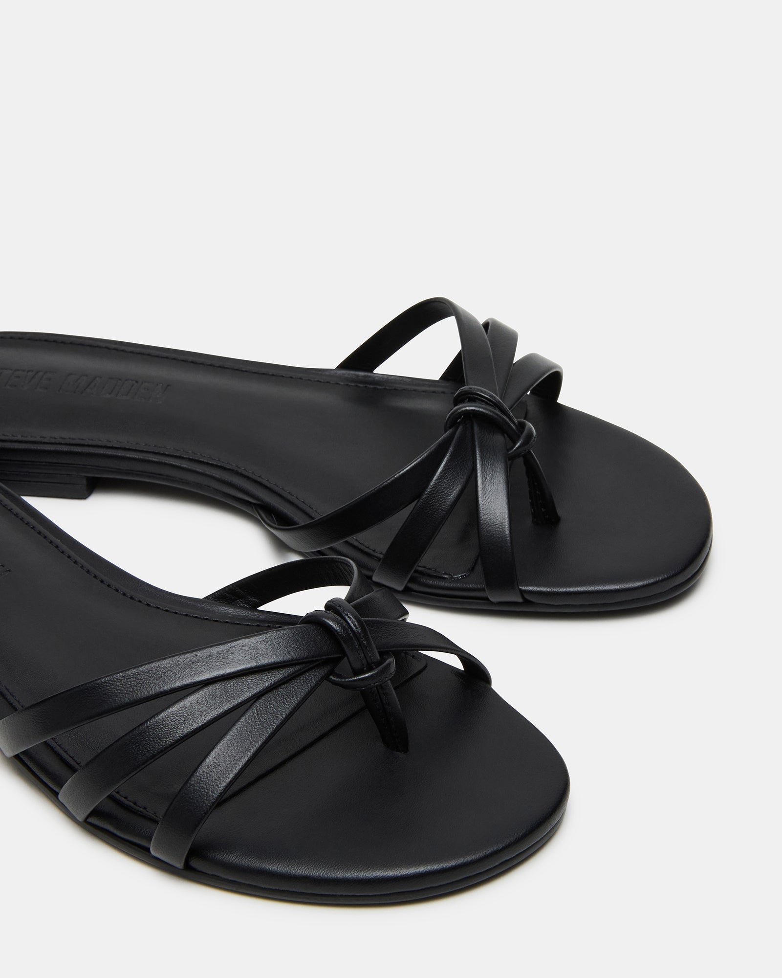 Calissi black flat sandals with strappy design on a white background.