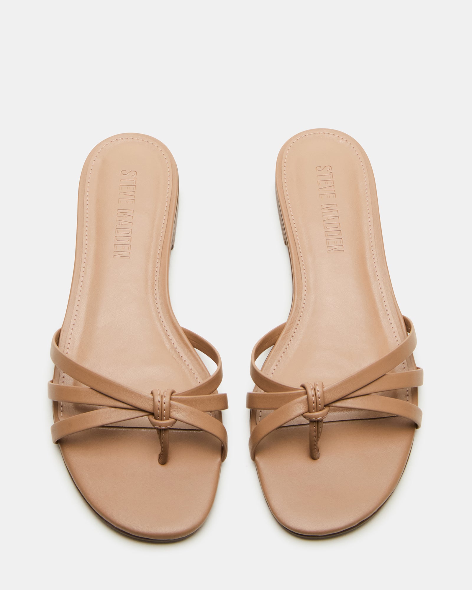 Top-down shot of black leather sandals styled with relaxed linen pants.