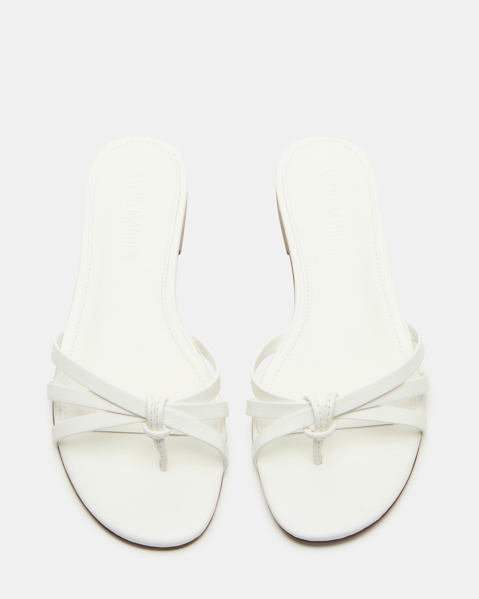 Close-up of white heeled sandals highlighting the strappy design.