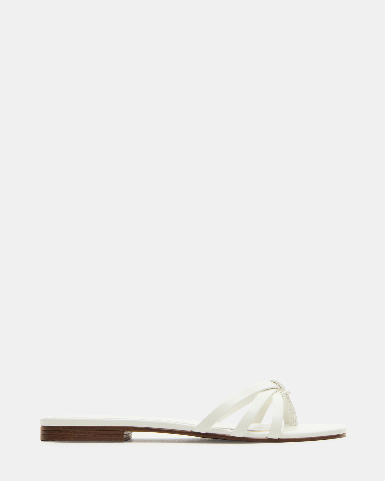 Calissi white wedge sandals displayed on a model at a beach party.