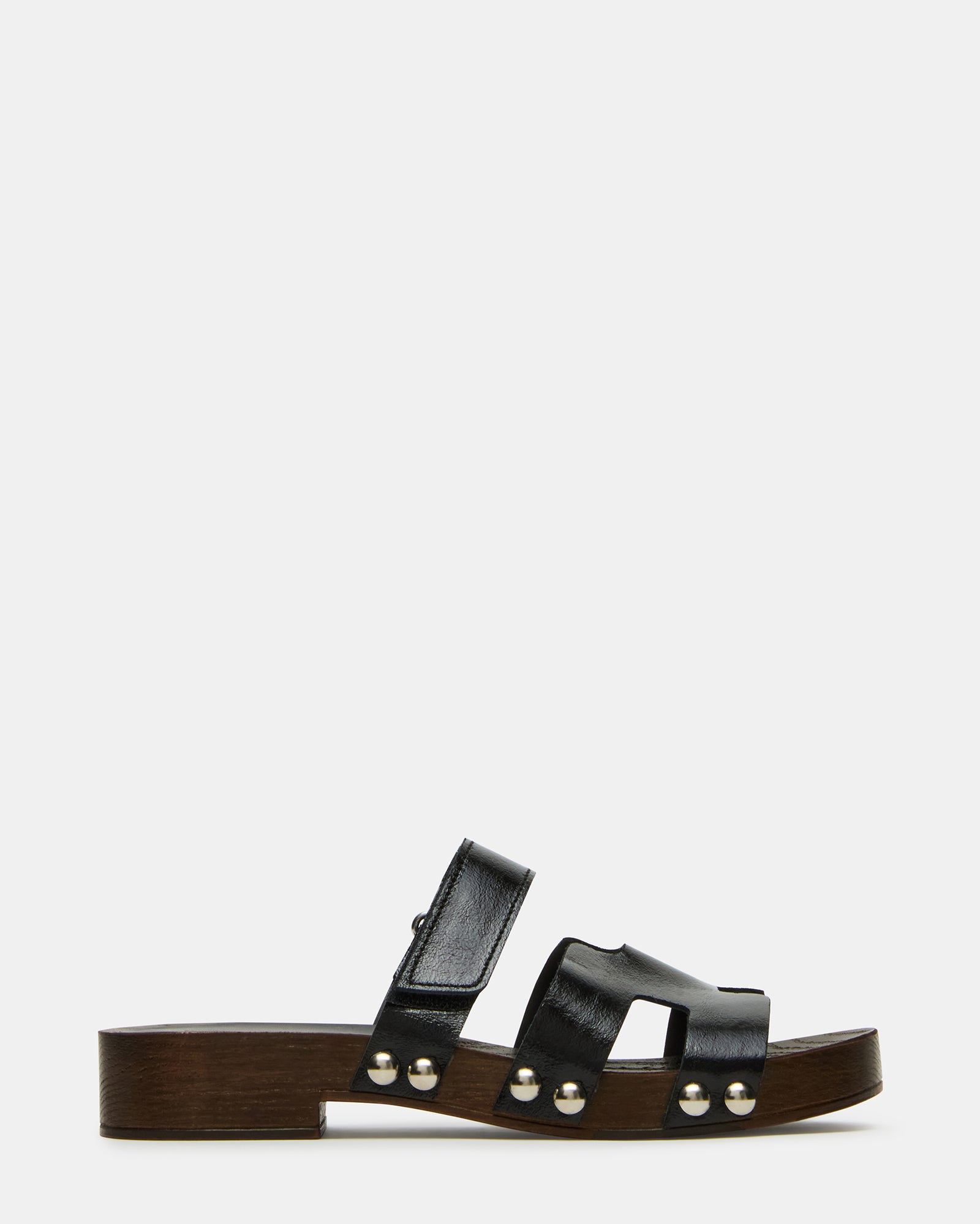 Side view of Canal black patent slide sandals on a wooden surface.