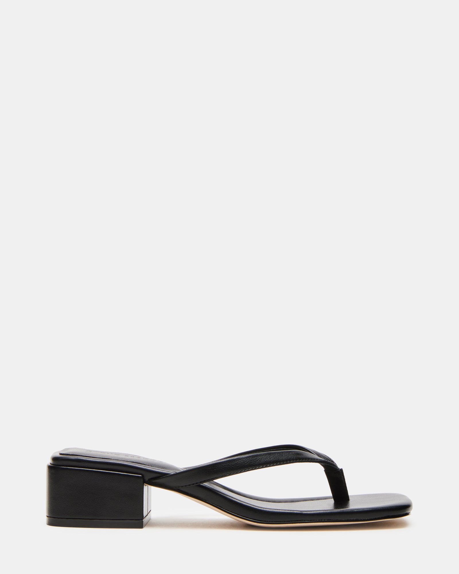 Caribbean black mule sandals on wooden deck, styled with a summer dress.