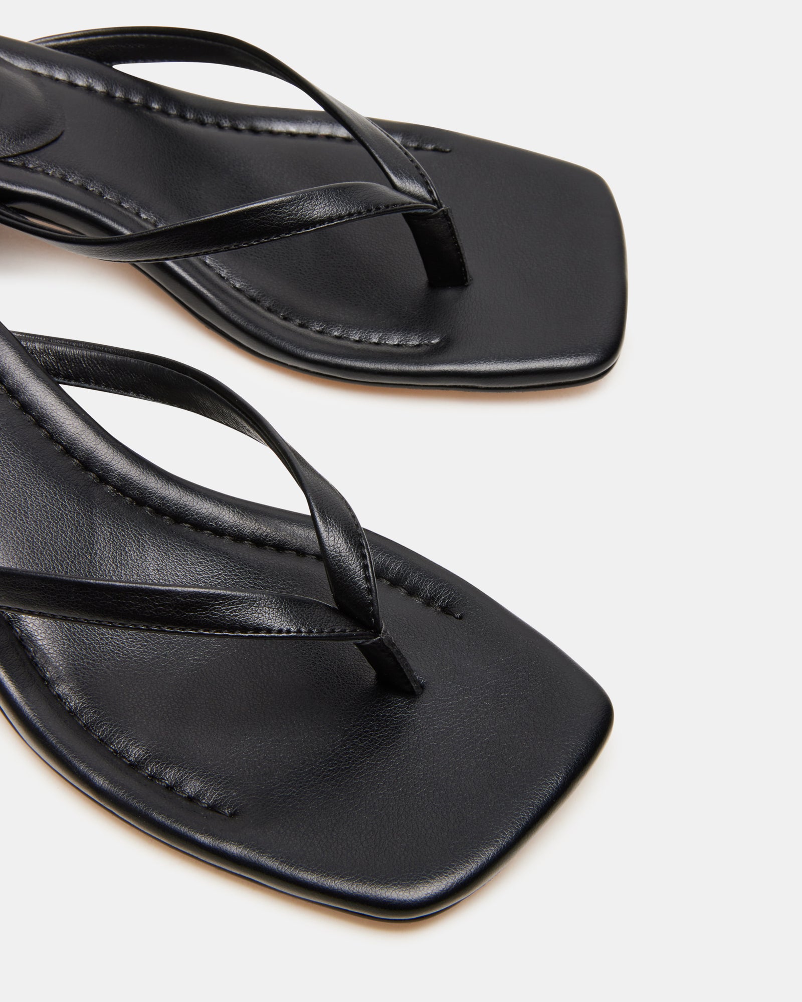 Caribbean black mule sandals on wooden deck, styled with a summer dress.