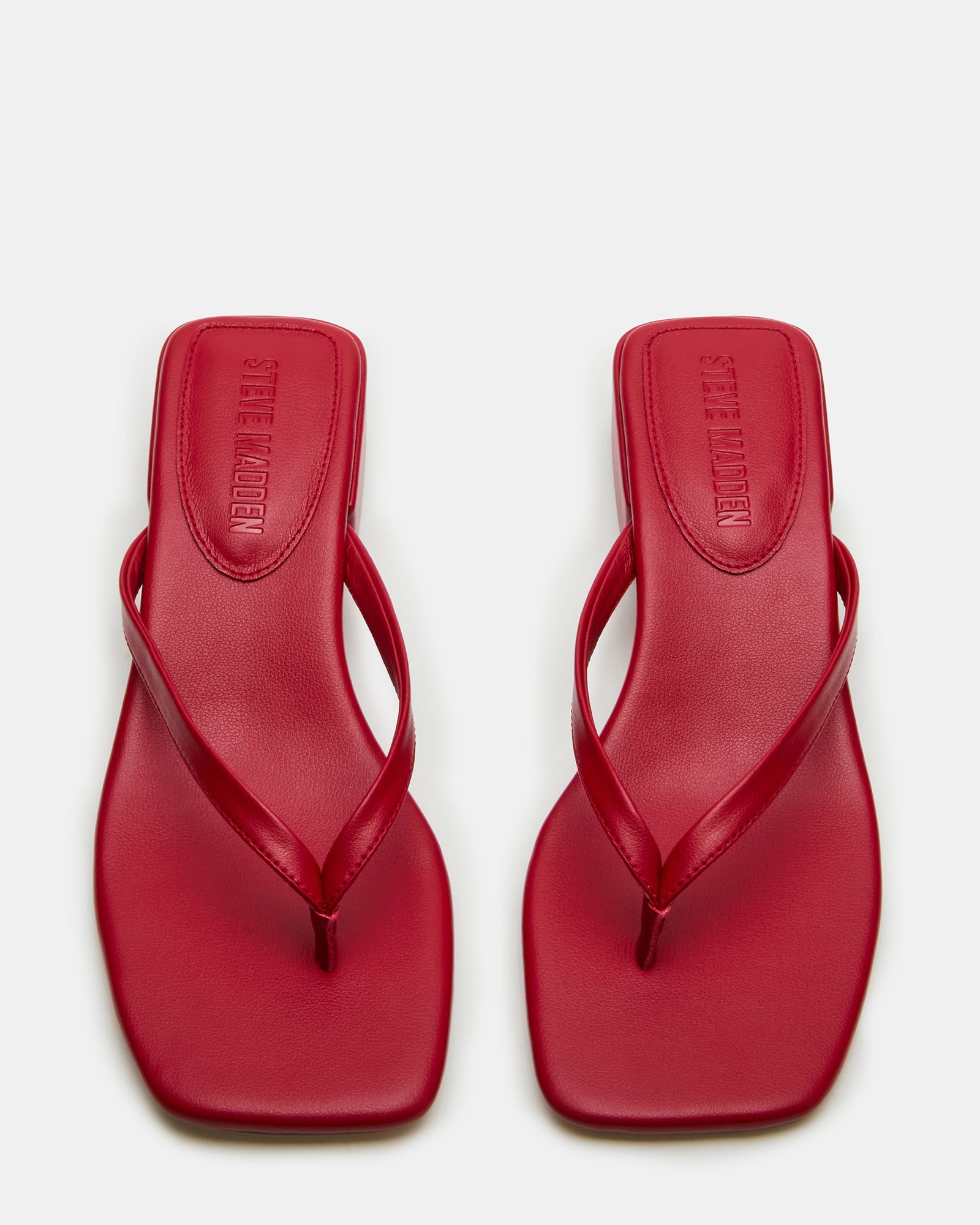 Side view of Caribbean Red square toe mule sandals on a beach.