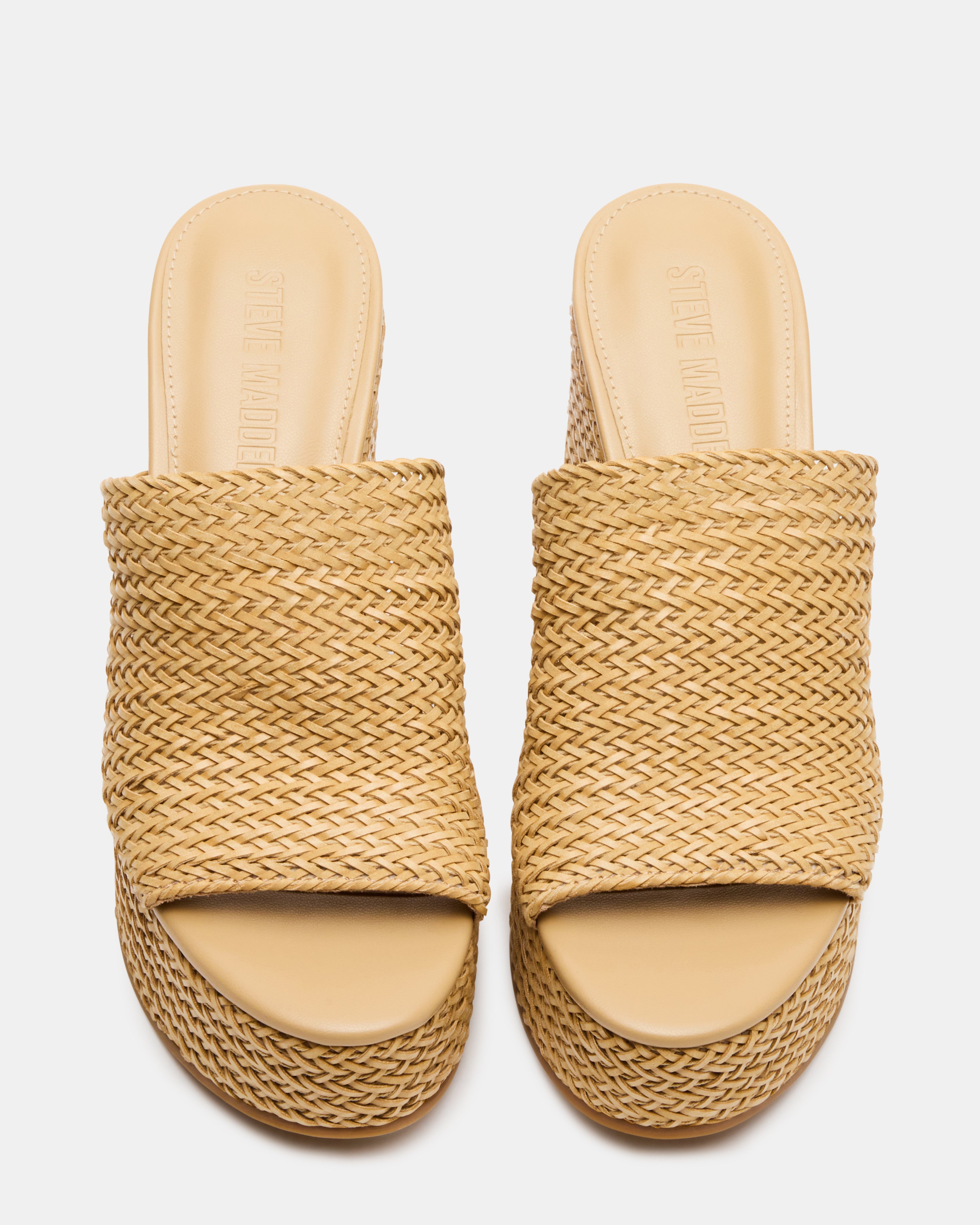 Side view of white wedge sandals with raffia detail shown on outdoor steps