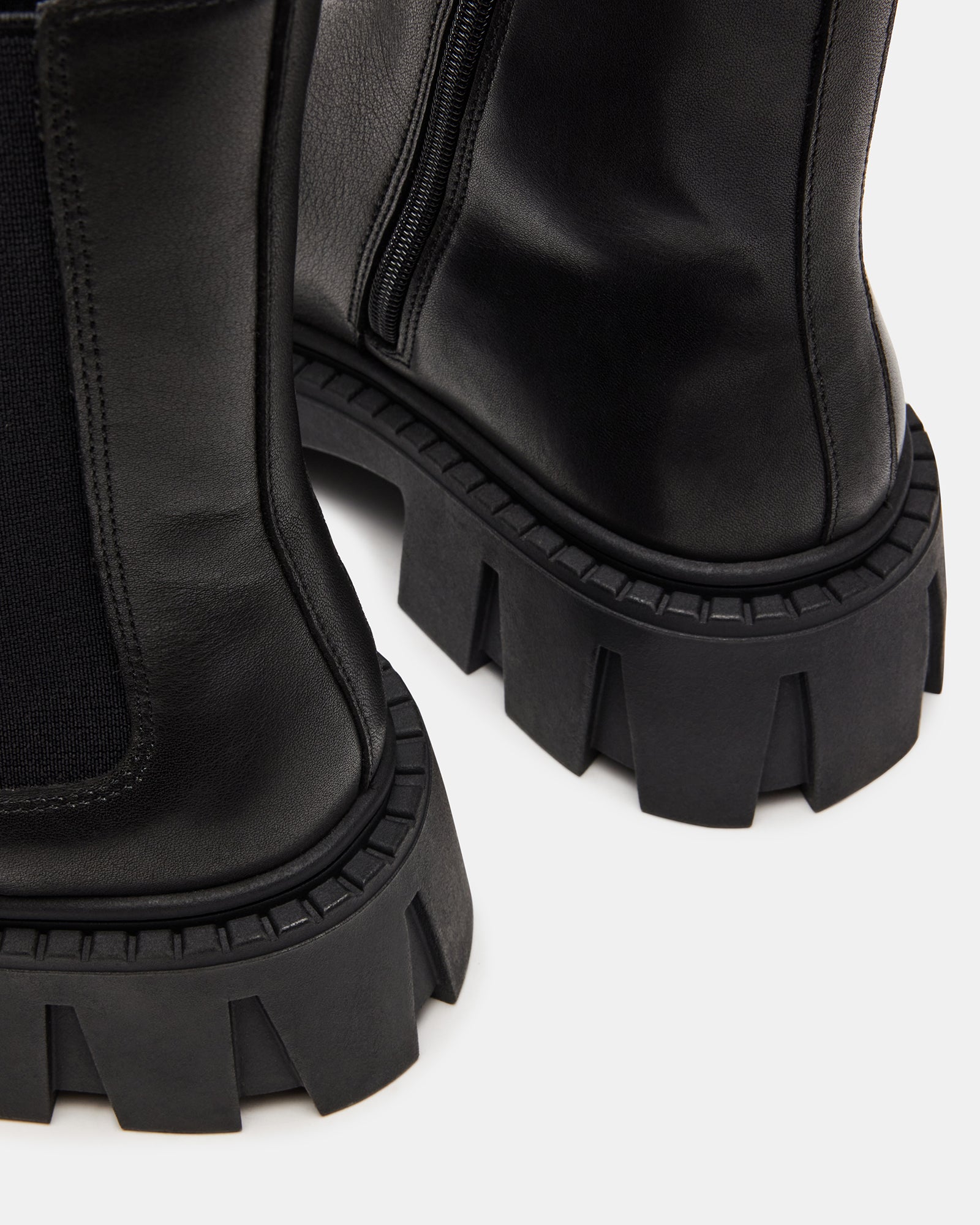 Close-up of the chunky lug sole on black leather Chelsea boots.