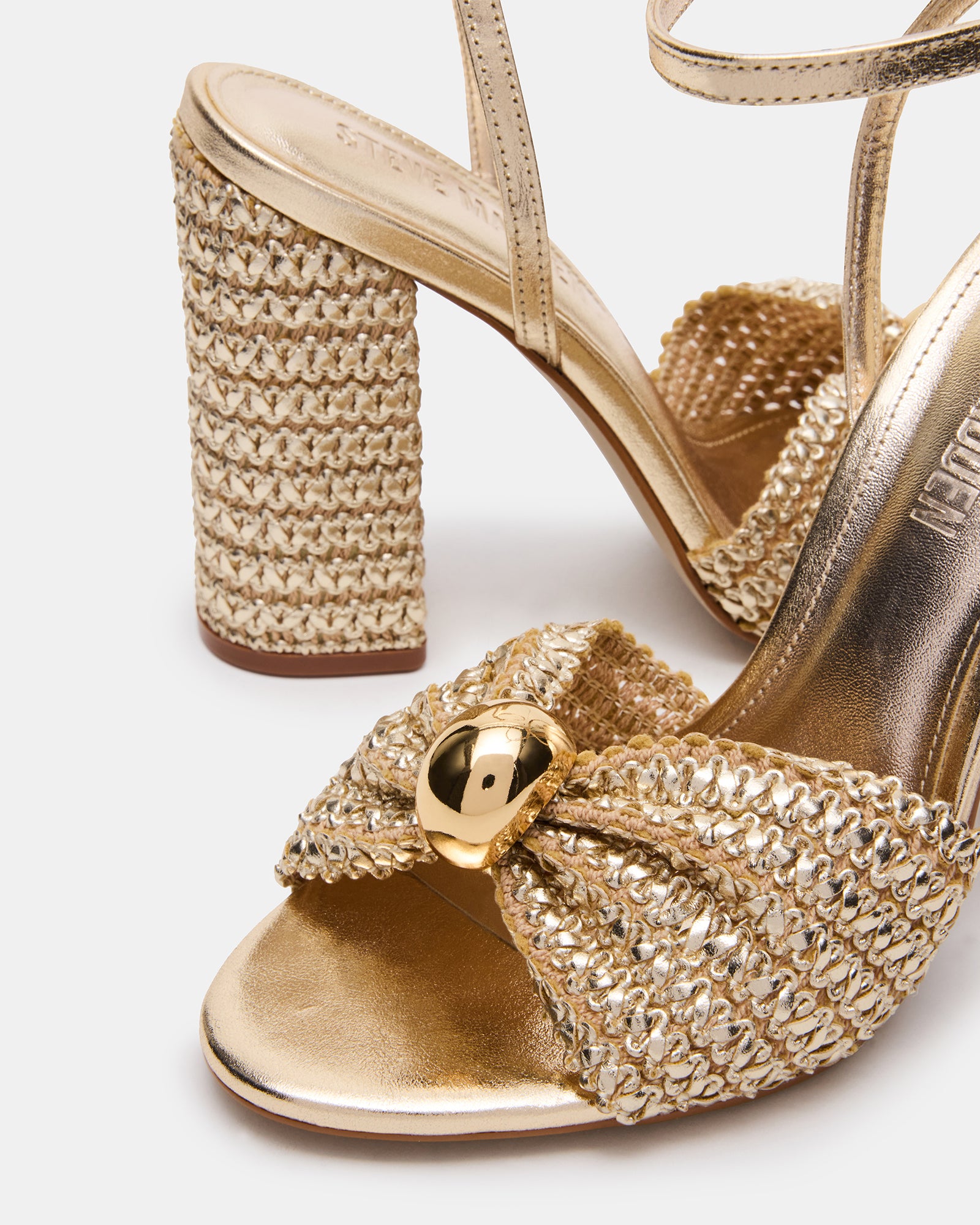 Close-up side view of the raffia-wrapped gold block heel sandals on model feet