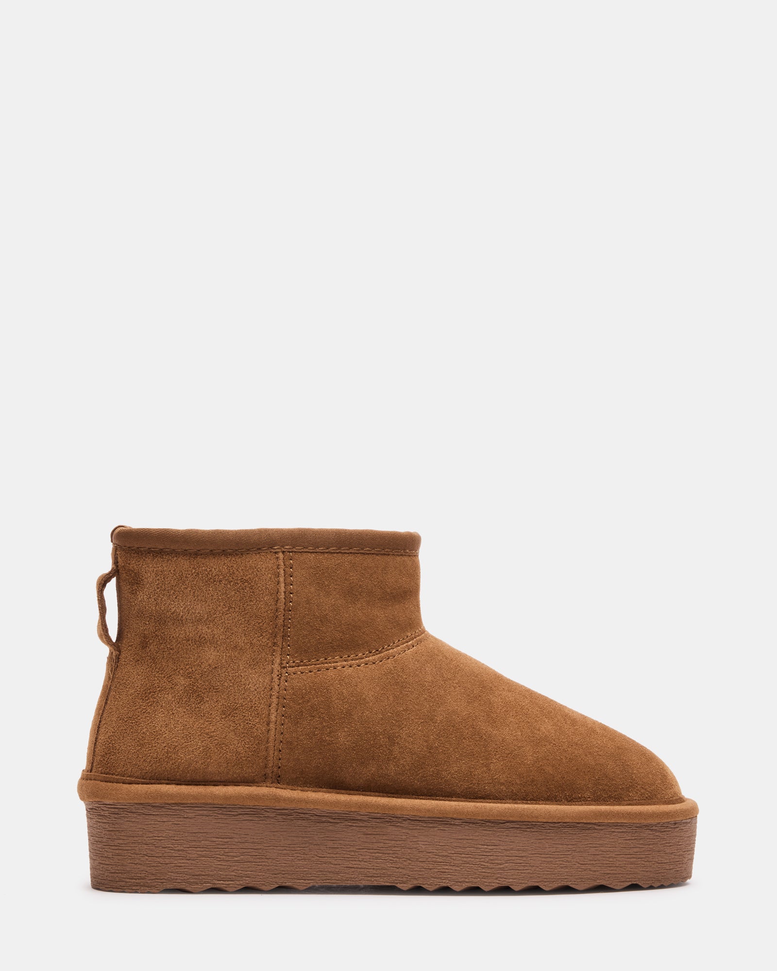 Women's ankle boots with faux fur detail, worn with jeans in a city setting.
