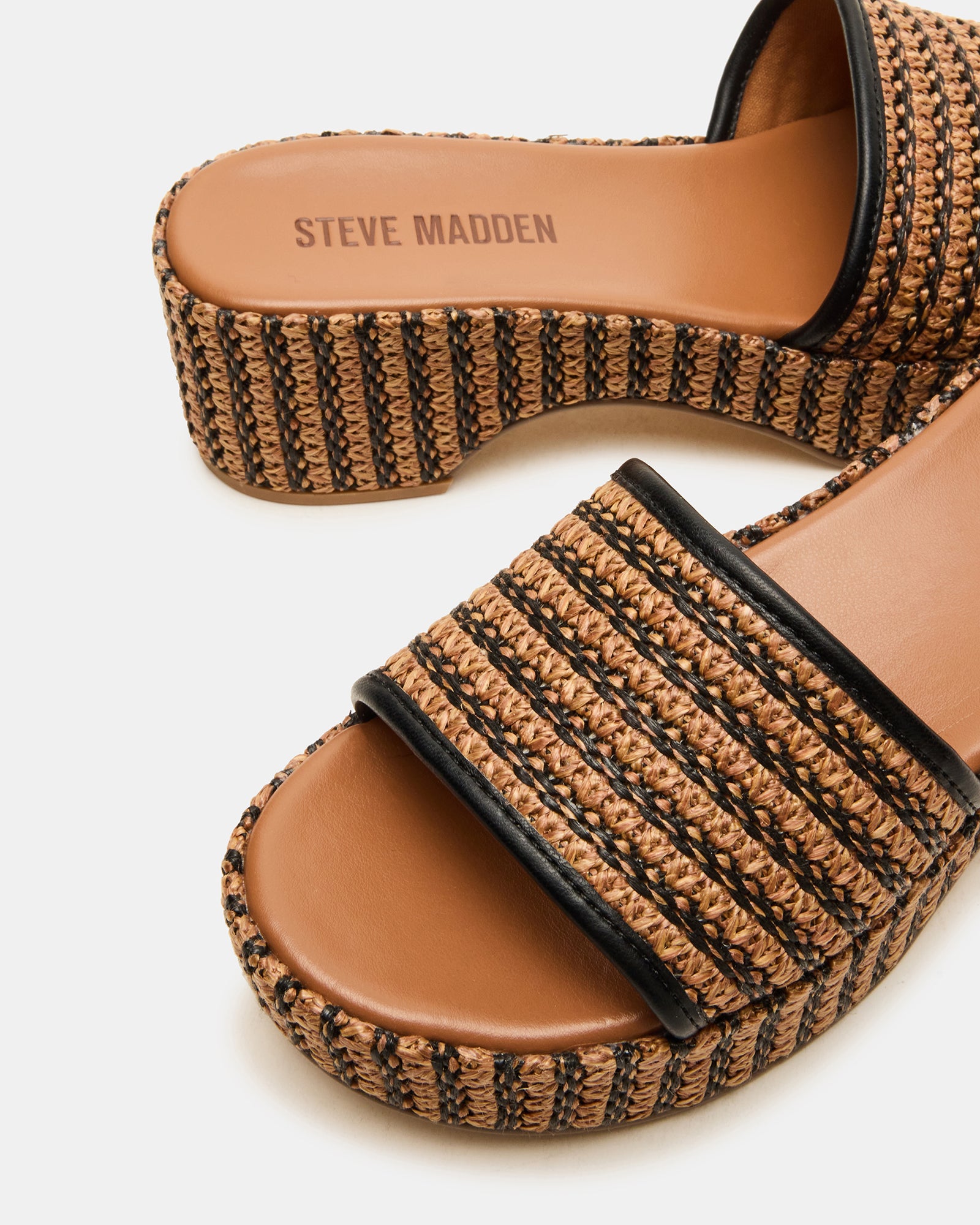 Black platform sandals arranged beside summer accessories like sunglasses and woven tote