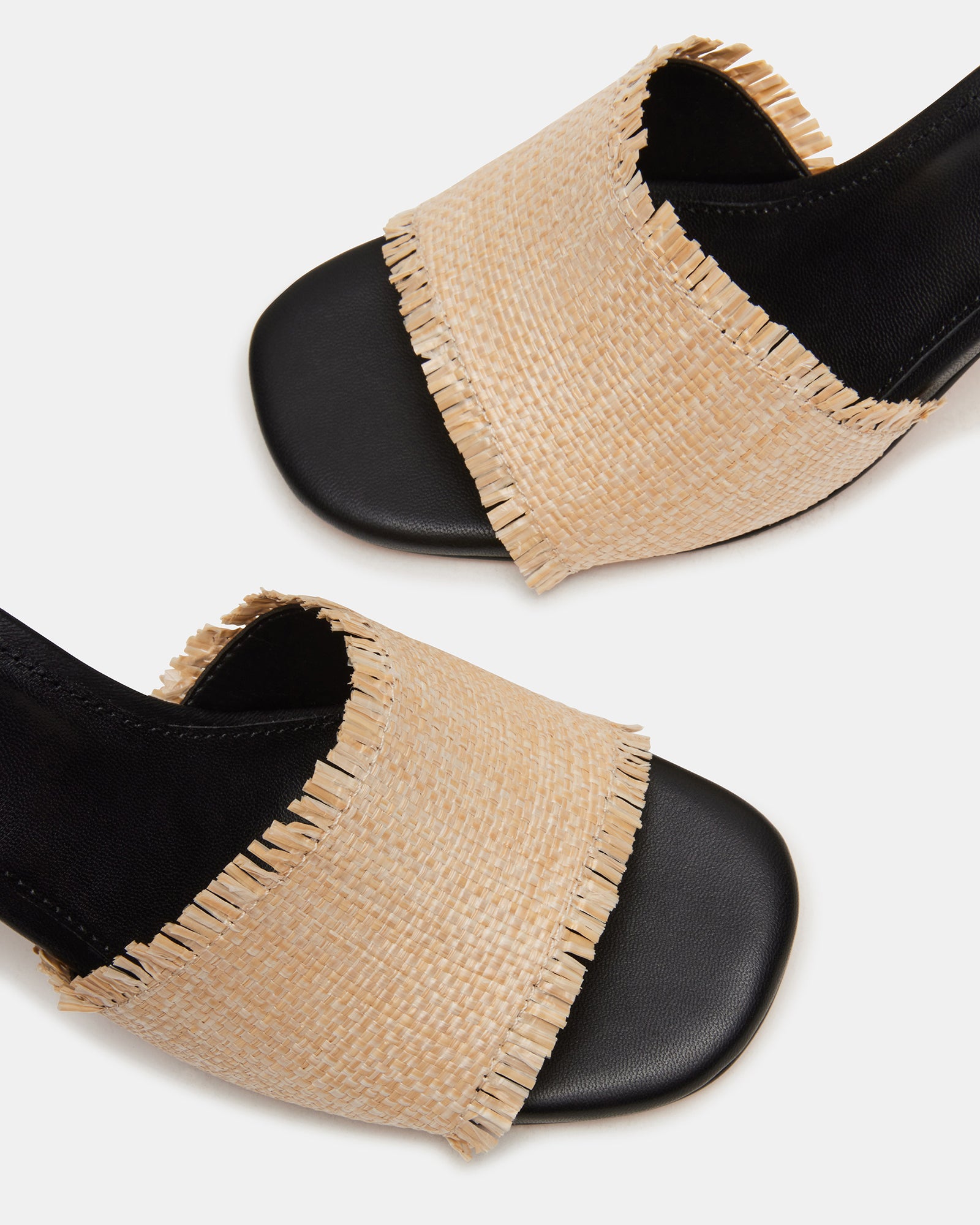 Close-up of raffia kitten heels highlighting the weave and heel shape.