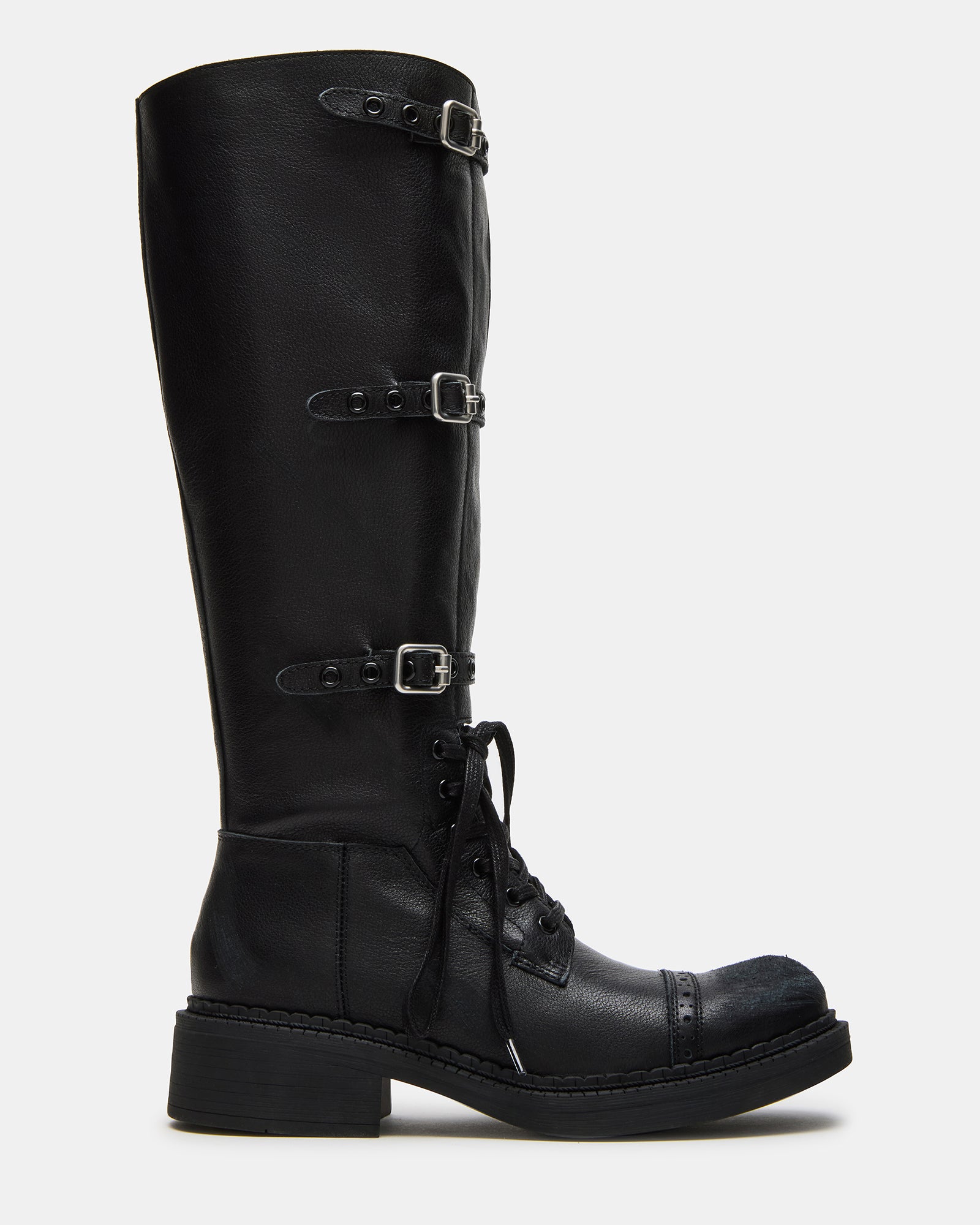Side view of men's square toe boots on textured concrete