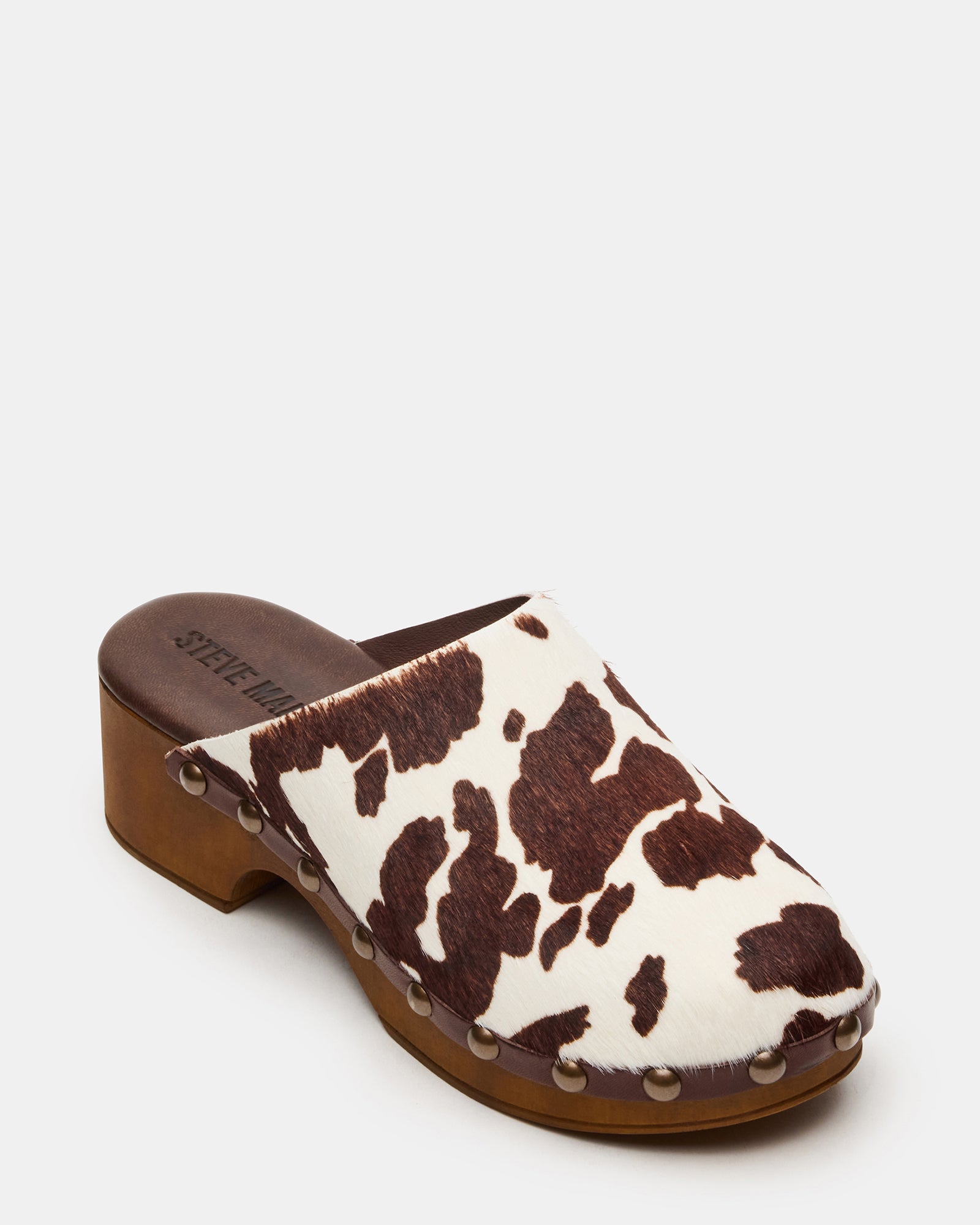 Side profile of brown leather mule shoes on hardwood floor, highlighting heel