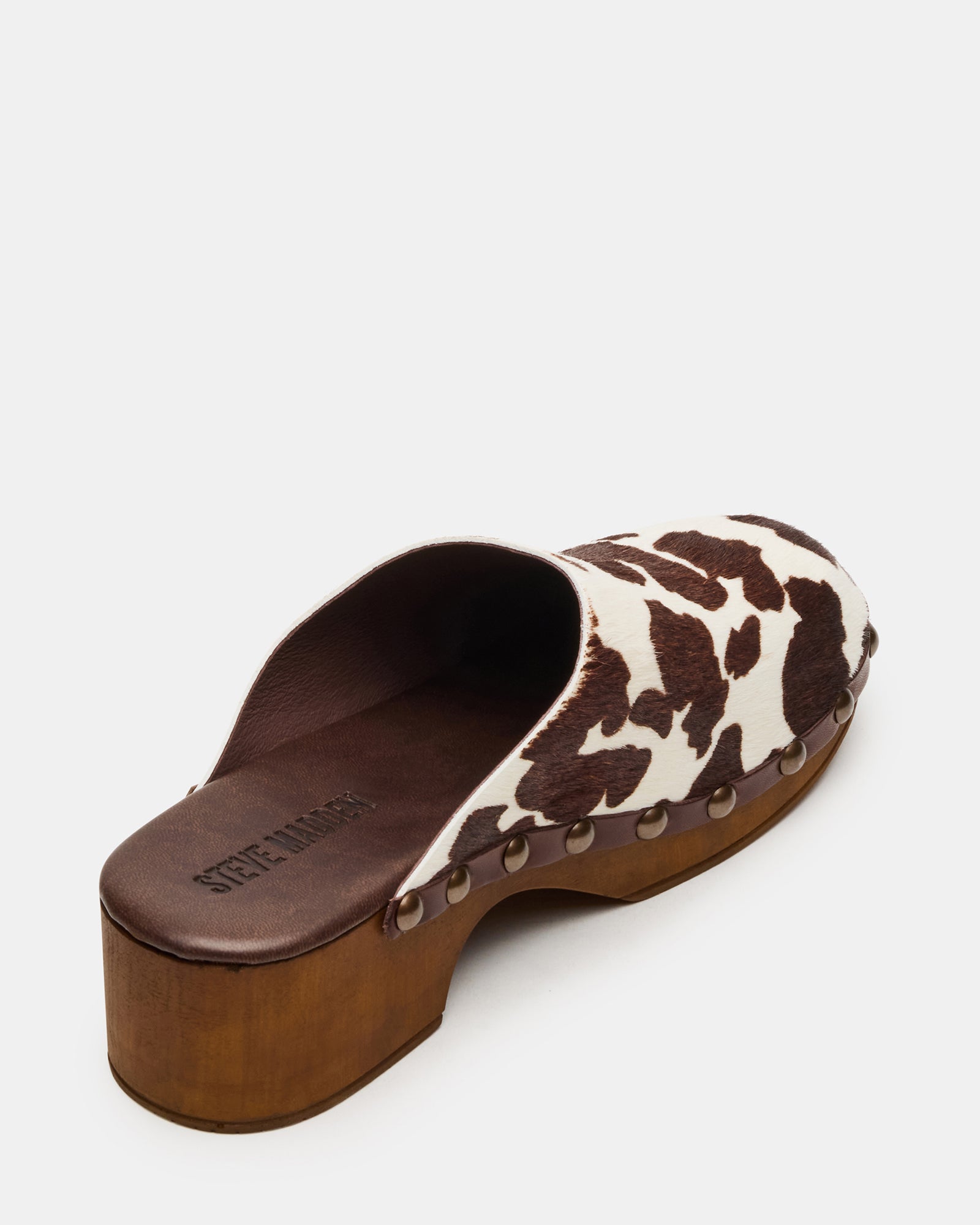 Side profile of brown leather mule shoes on hardwood floor, highlighting heel