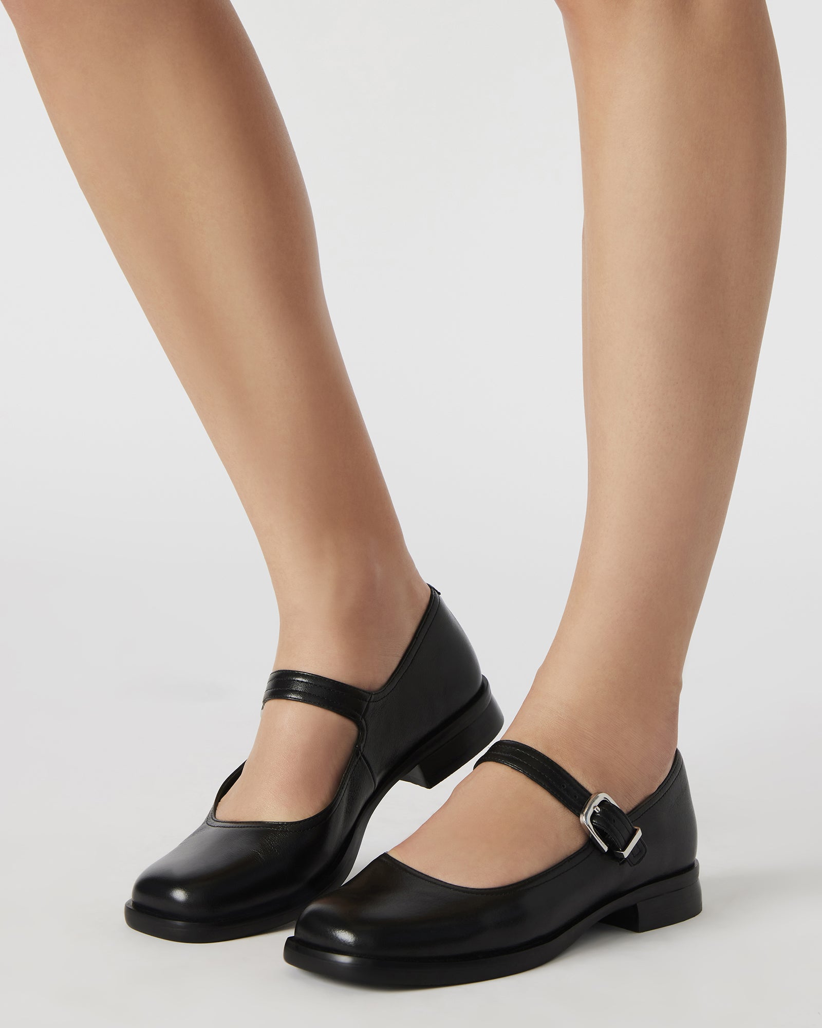 Close-up of black mary jane shoes strap and stitched leather material.