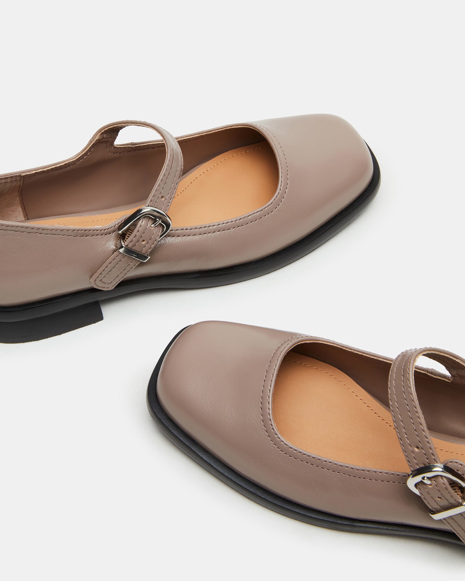 Close-up of black mary jane shoes strap and stitched leather material.