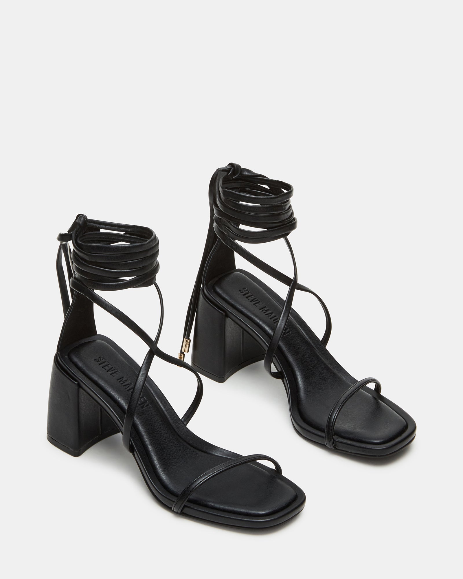 Black block high heel shoes styled with tailored trousers in an outdoor SoCal café setting