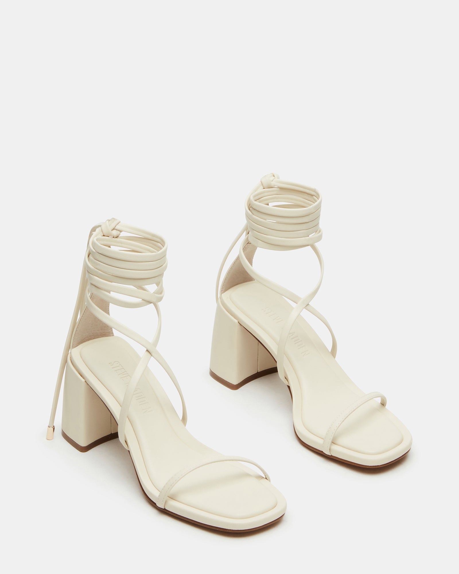 Side view of nude strappy block heel sandals on a wooden floor