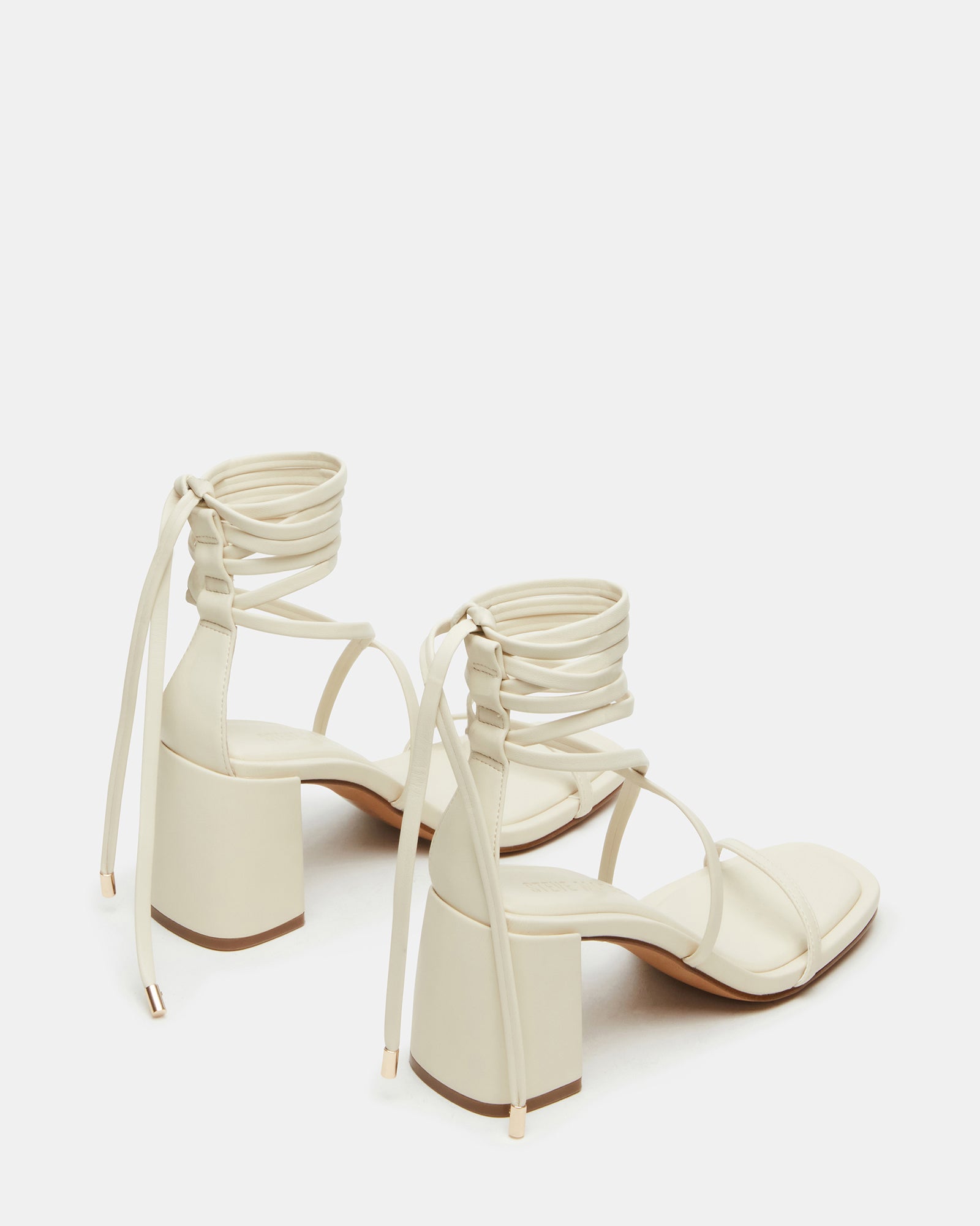 Side view of nude strappy block heel sandals on a wooden floor