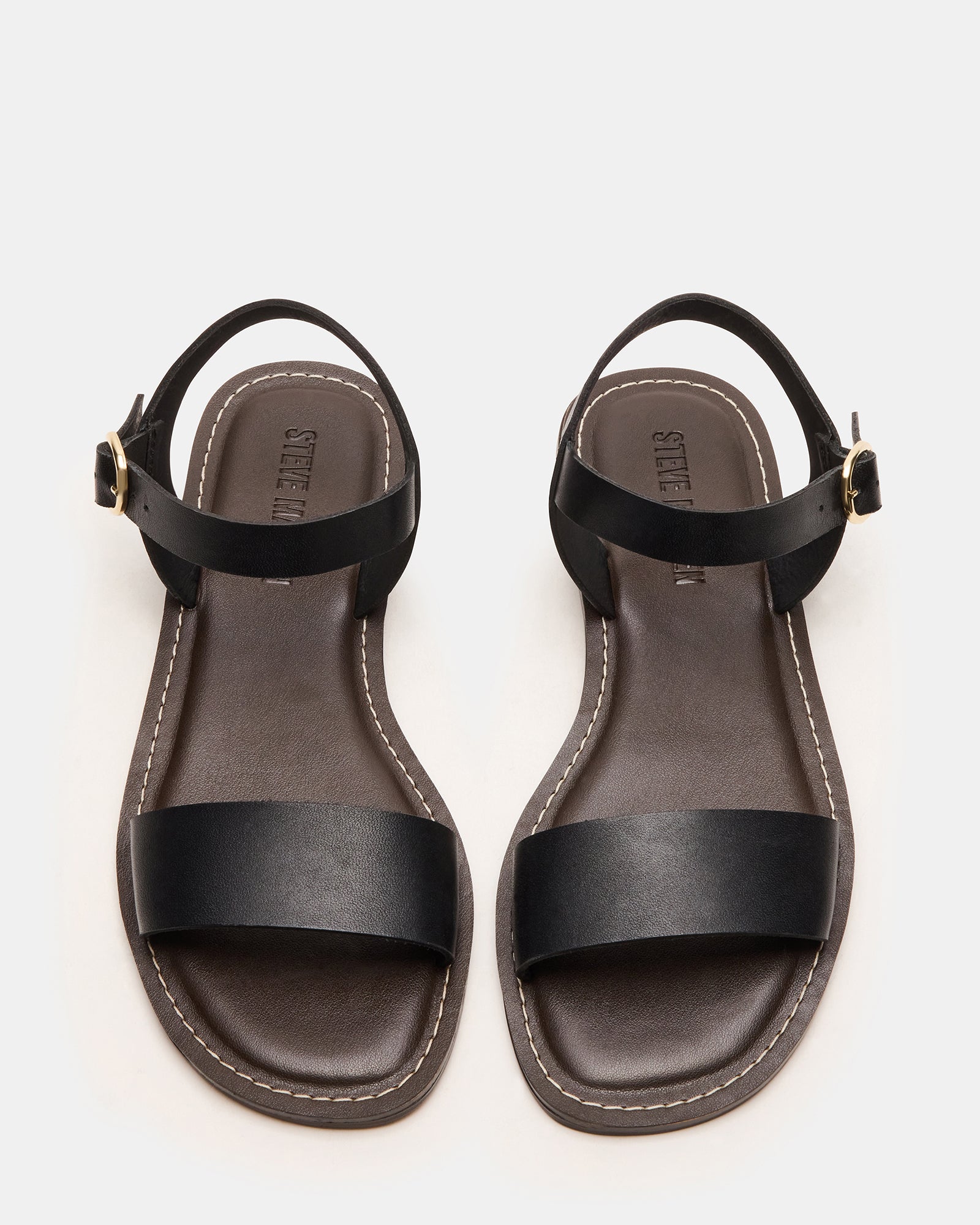 Close-up of stylish black flat sandals, emphasizing the premium leather material.