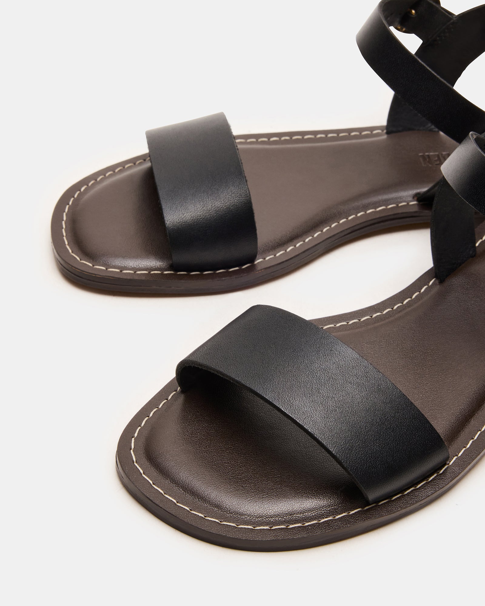 Black leather flat sandals showcasing a sleek design, ideal for casual wear.