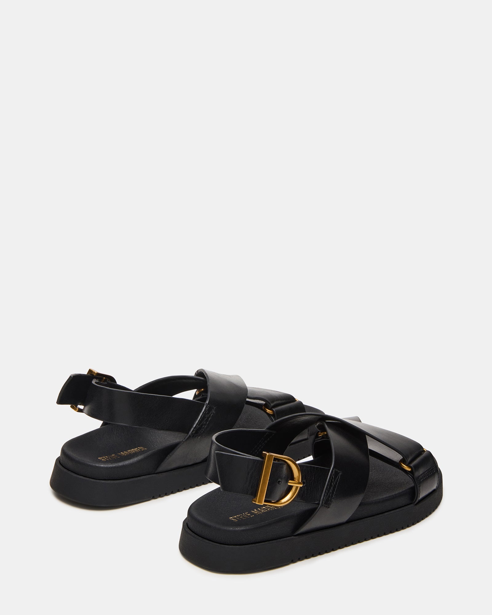 Close-up of the buckle detail on black strappy sandals.