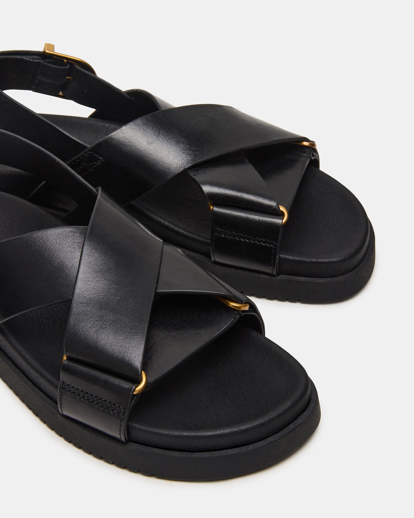 Model wearing elegant black leather sandals at a summer event.