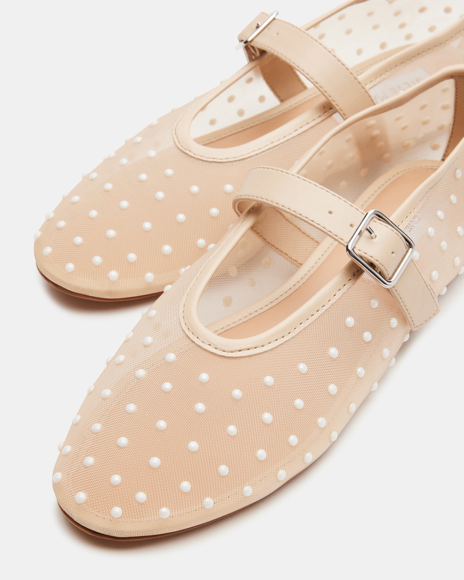Elegant ivory ballet flats highlighted in a fashion display.