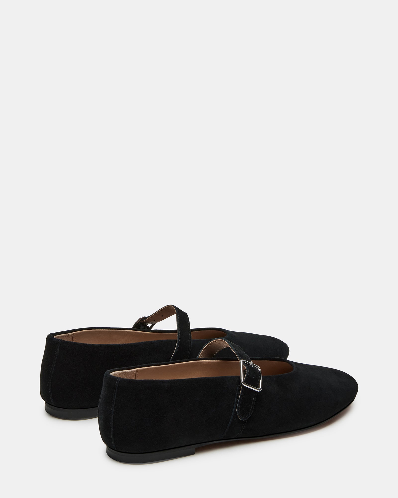 Black suede mary jane ballet flats worn during a fashionable city stroll.