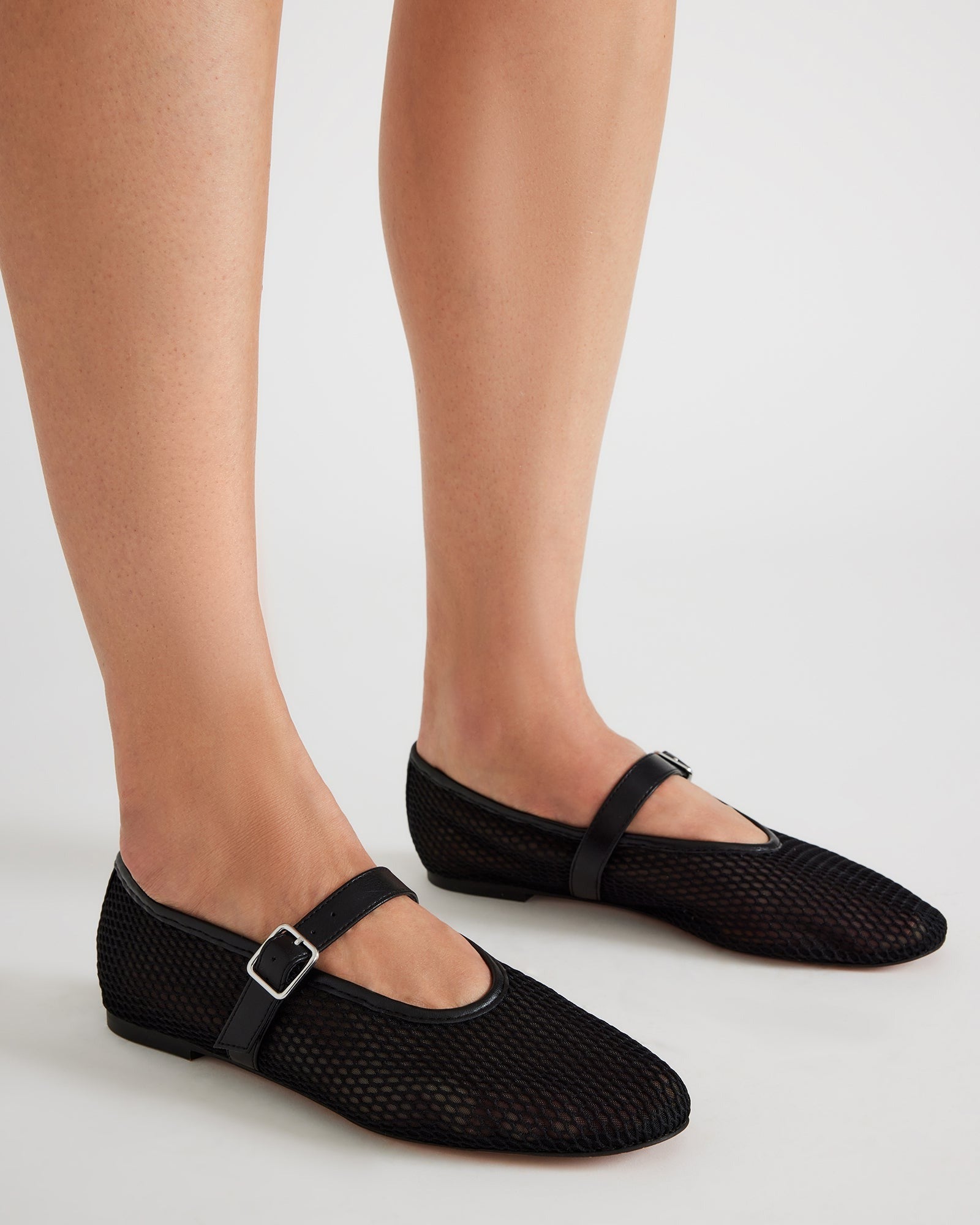 Front view of vegan ballet flats on a wooden floor, highlighting the textured upper.