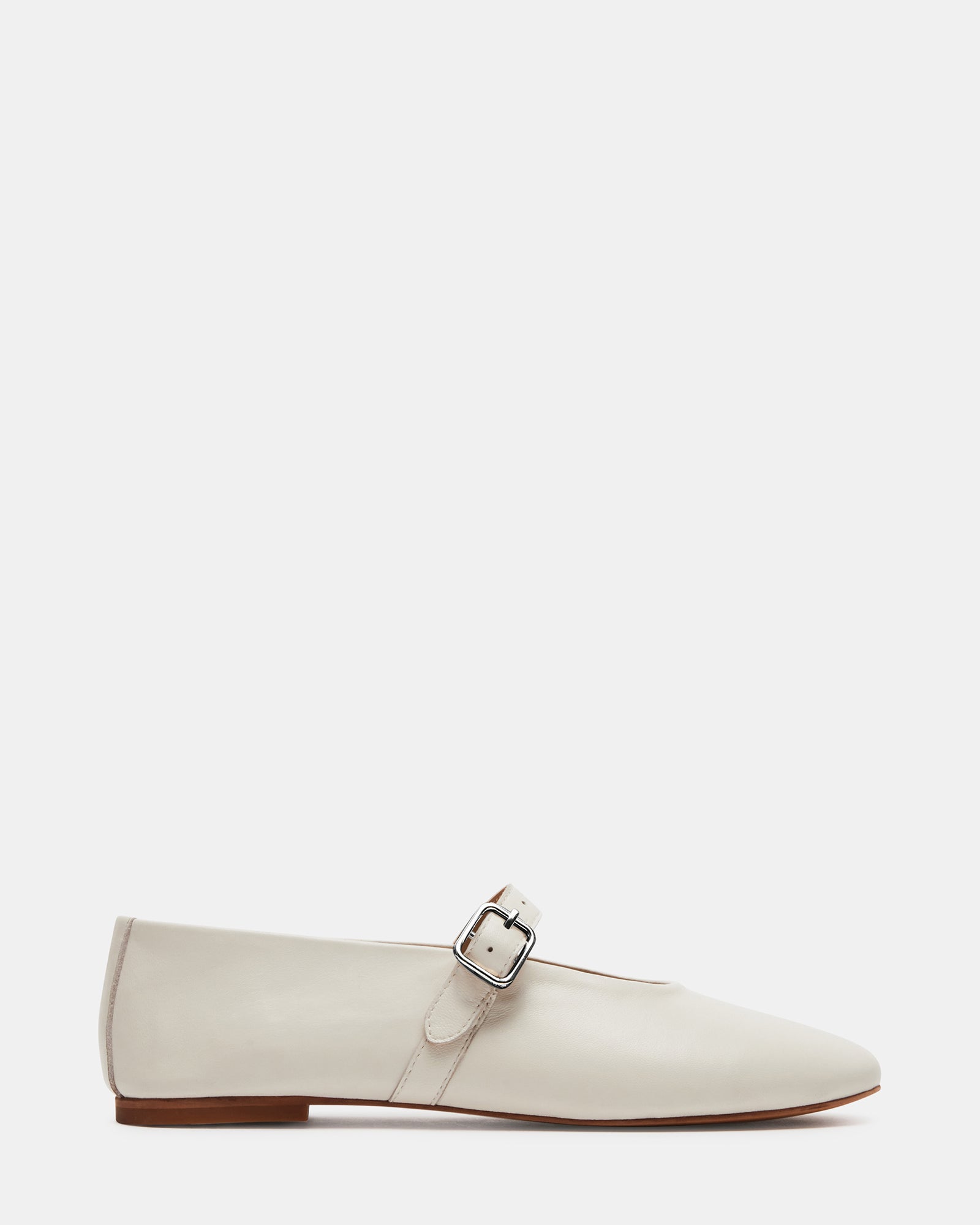 Front view of white patent leather ballet flats on wooden floor