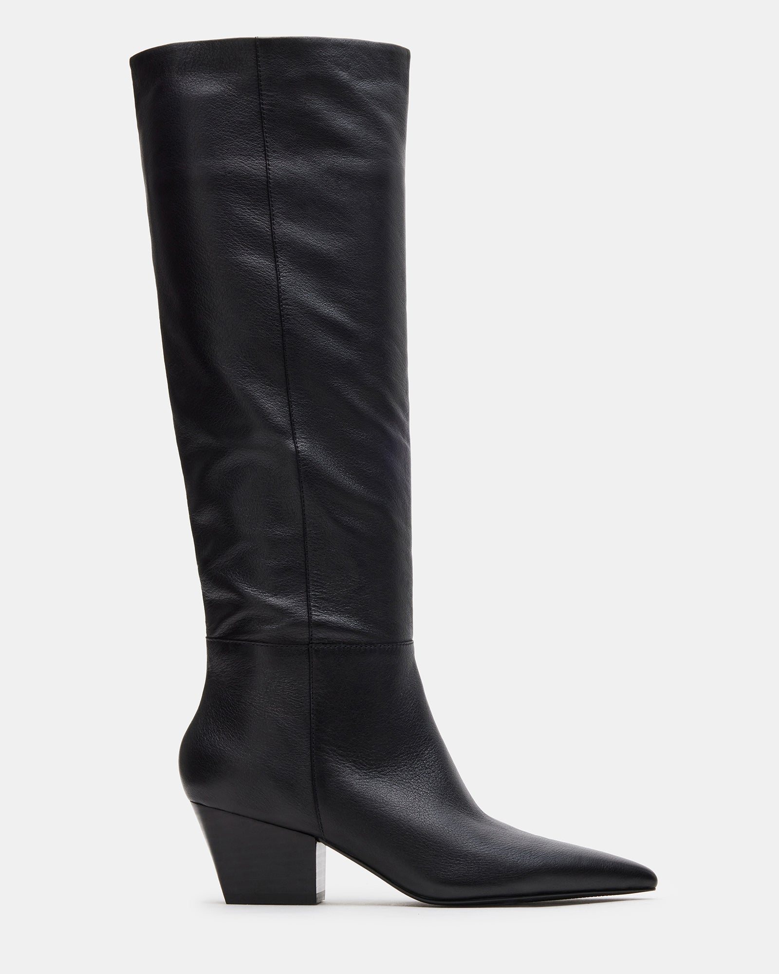 Side angle of black pointed toe boots styled over skinny jeans in urban fall setting.