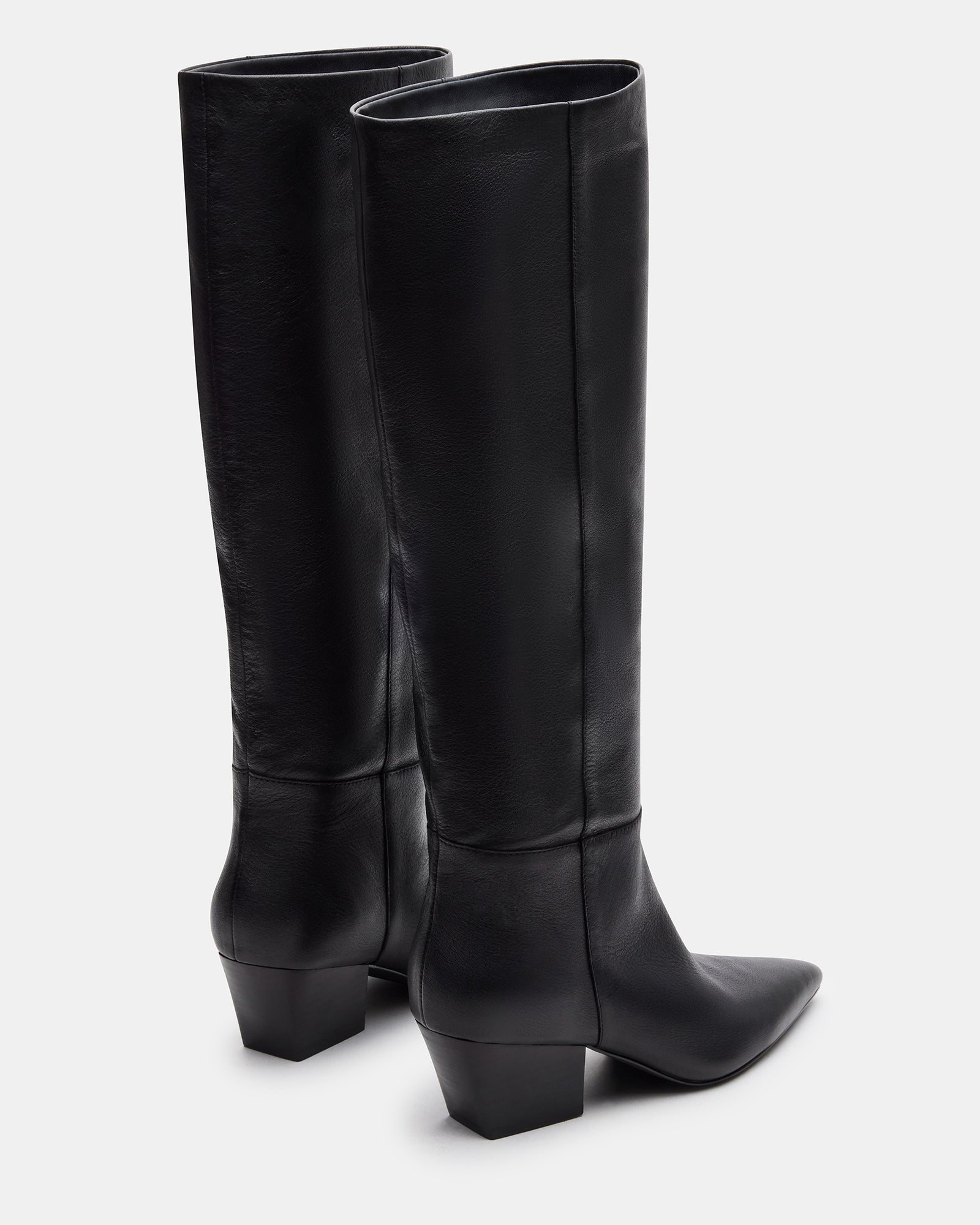 Close-up of knee high boots showing leather texture and sleek pointed silhouette.