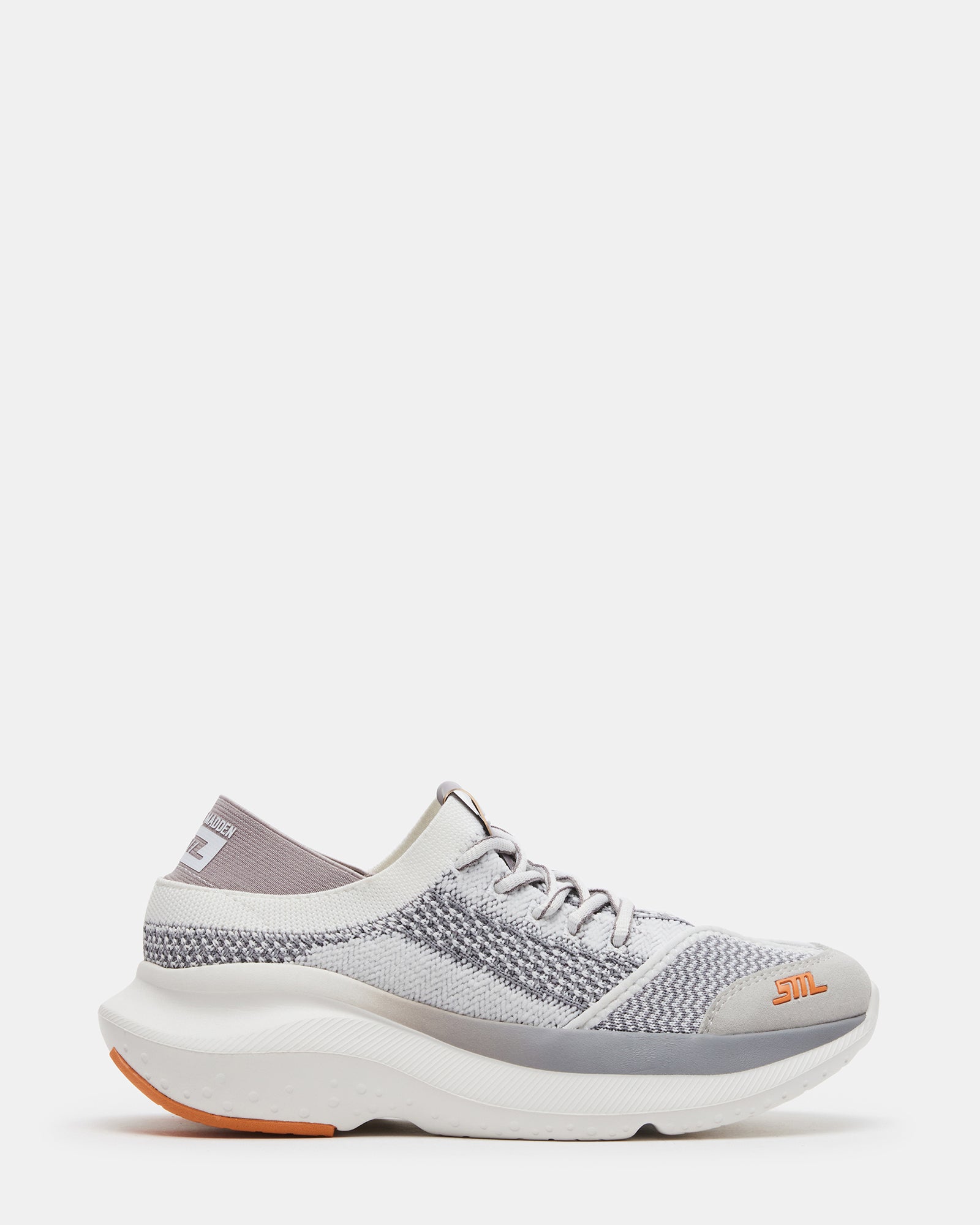 Front view of white platform sneakers with modern knit texture on a city street