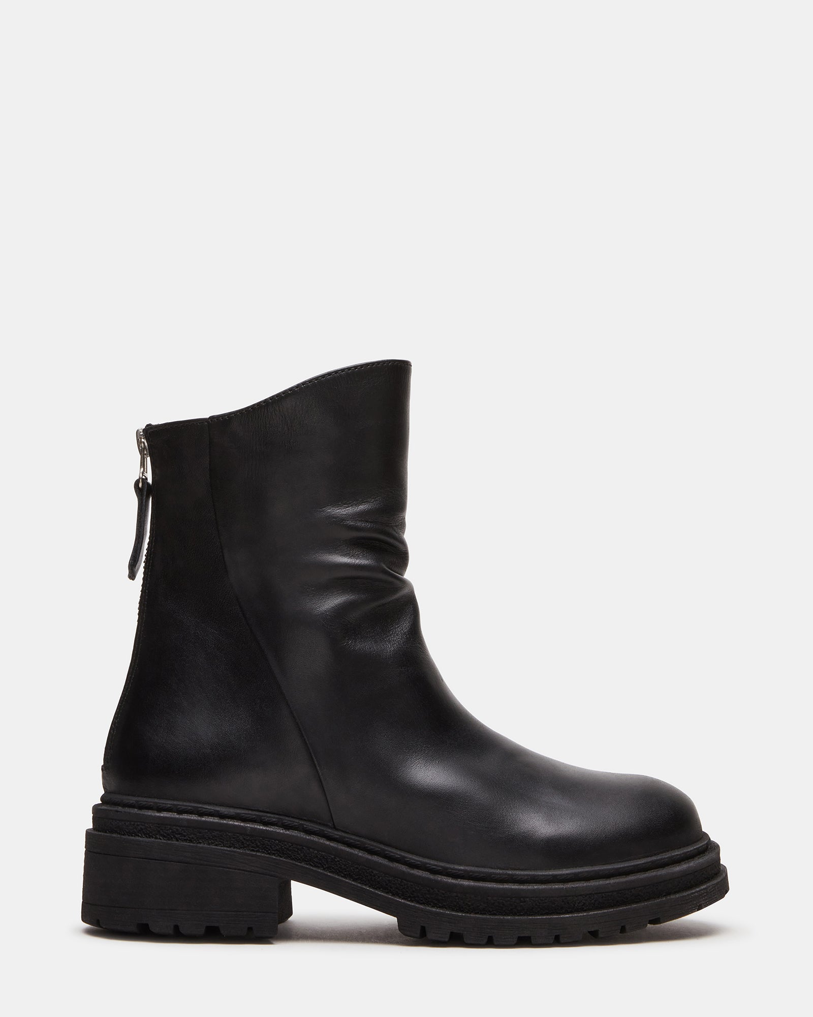 Side view of essential black leather ankle boots on a wooden surface.