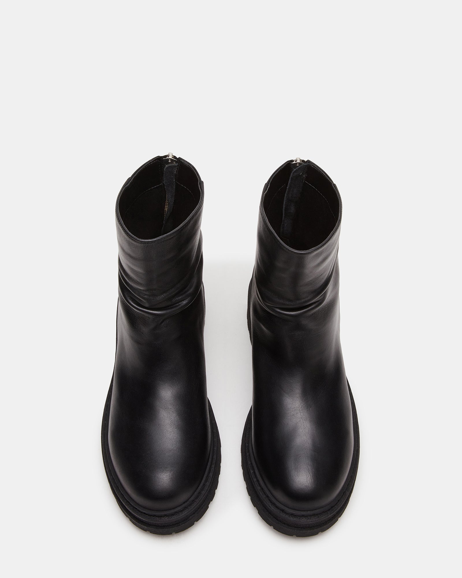 Side view of essential black leather ankle boots on a wooden surface.