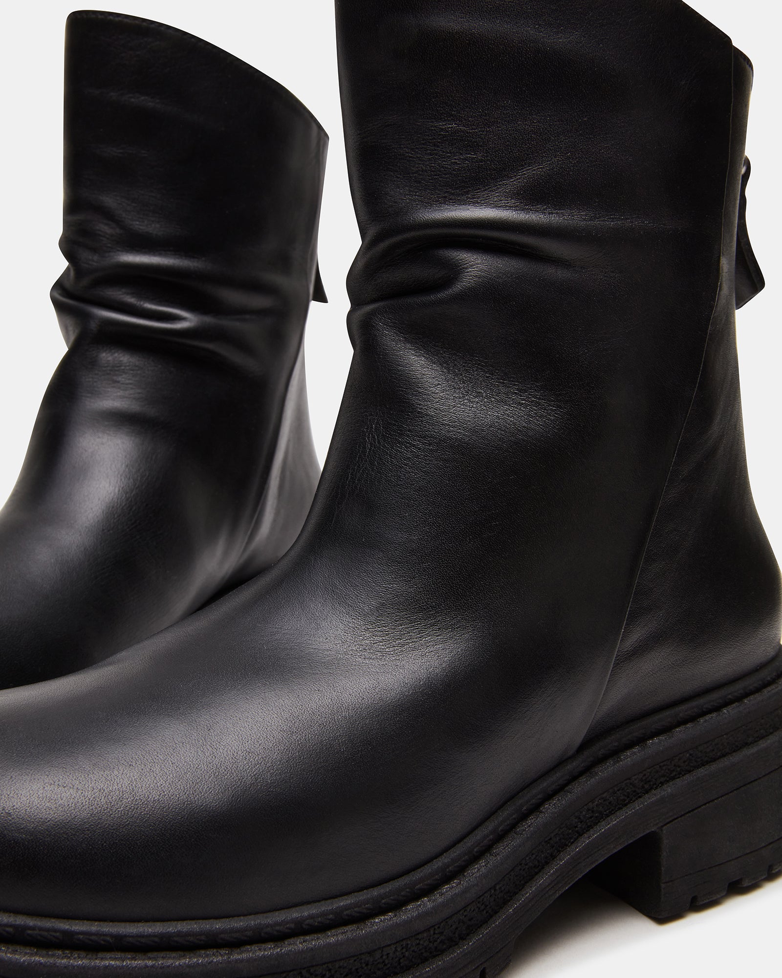 Model wearing black leather boots with casual outfit outdoors.