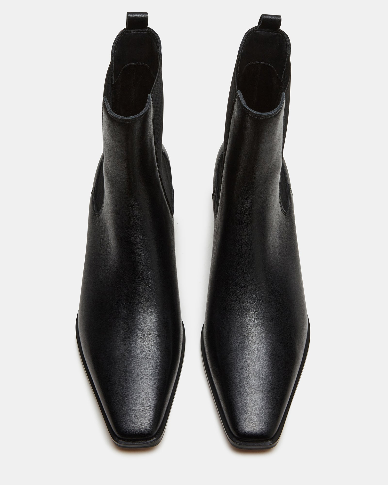 Black Chelsea boots styled with cuffed jeans for a casual look.