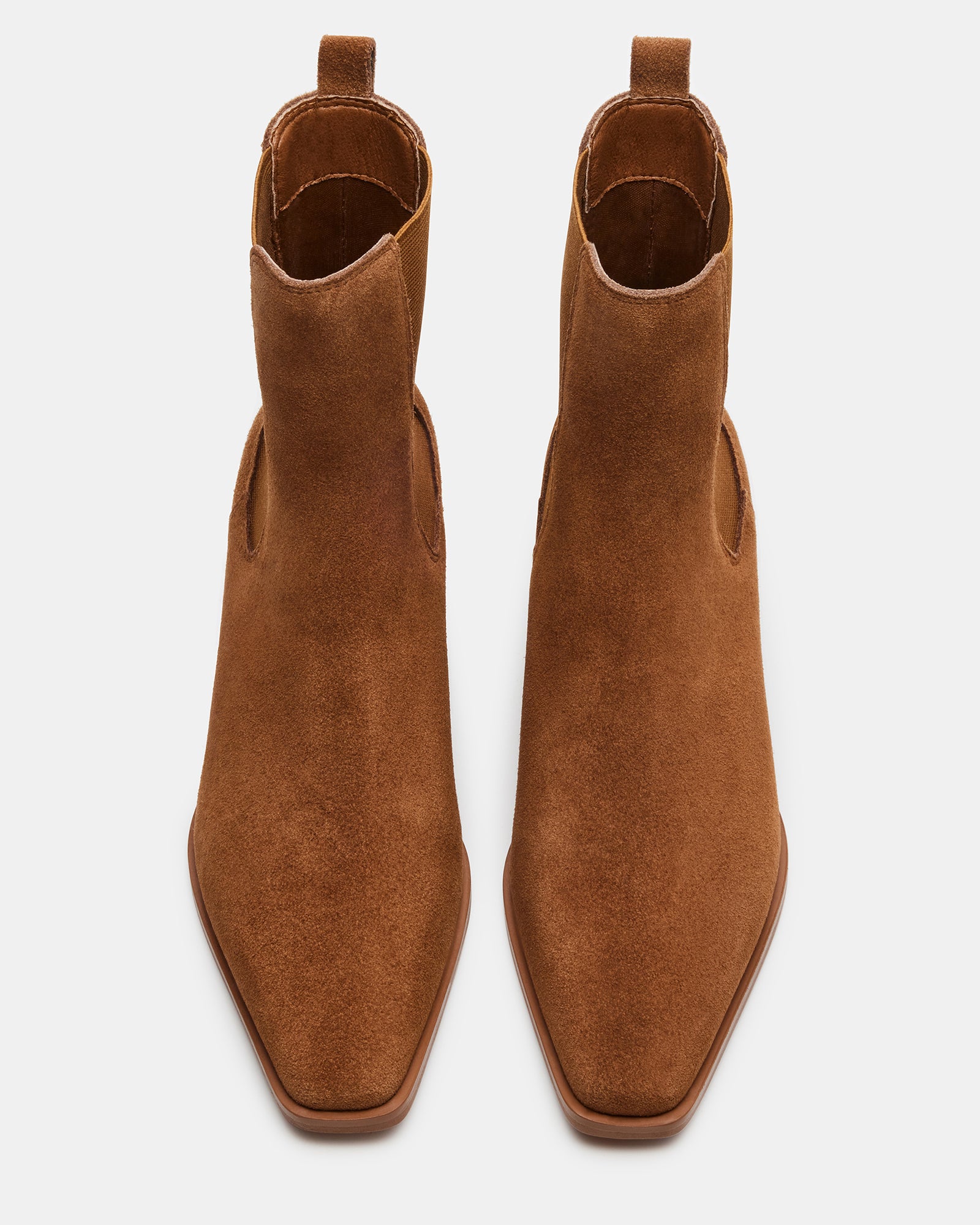 Side view of brown suede Chelsea boots on a wooden floor