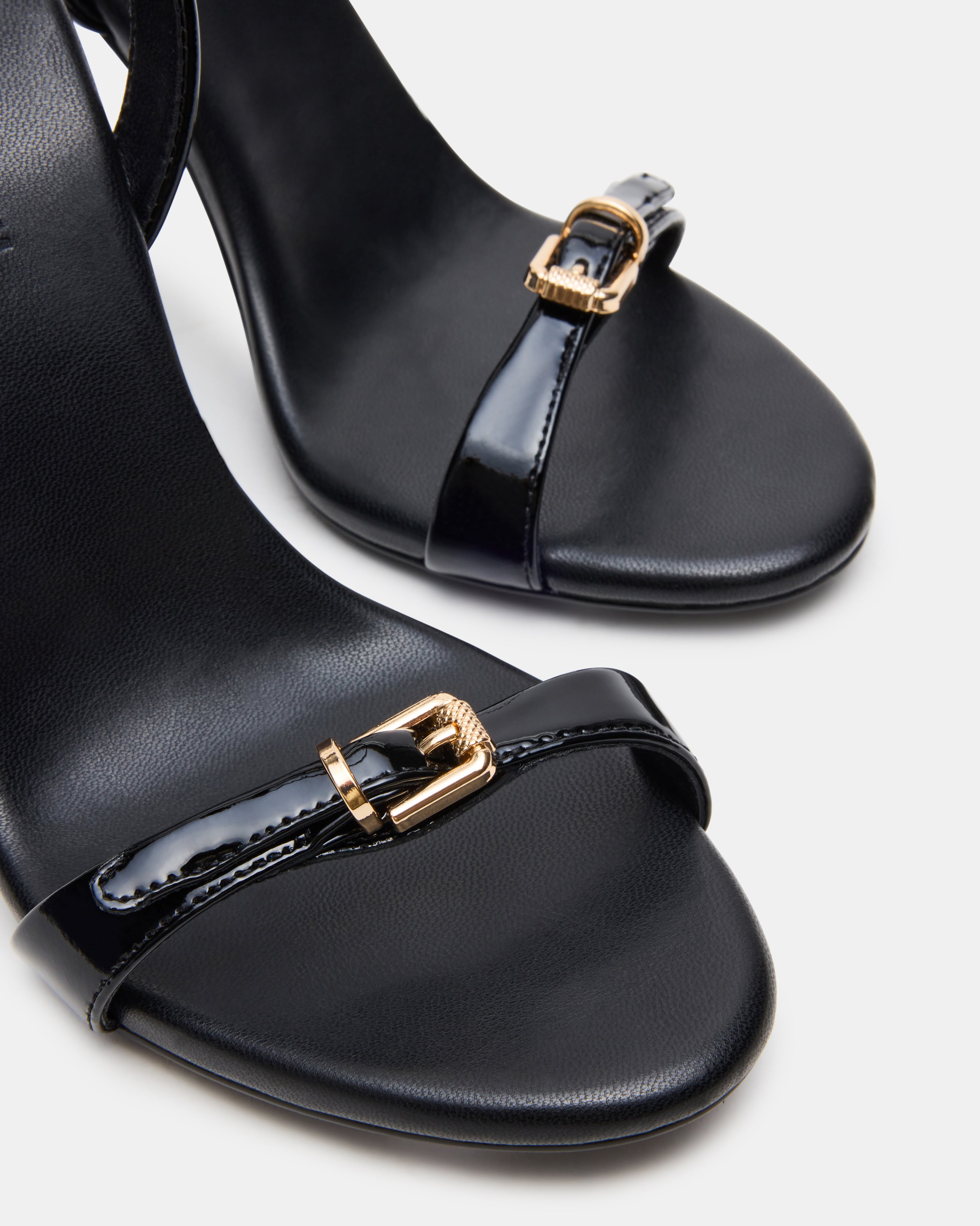 Close-up of FOXX black stiletto heels with buckle detailing.