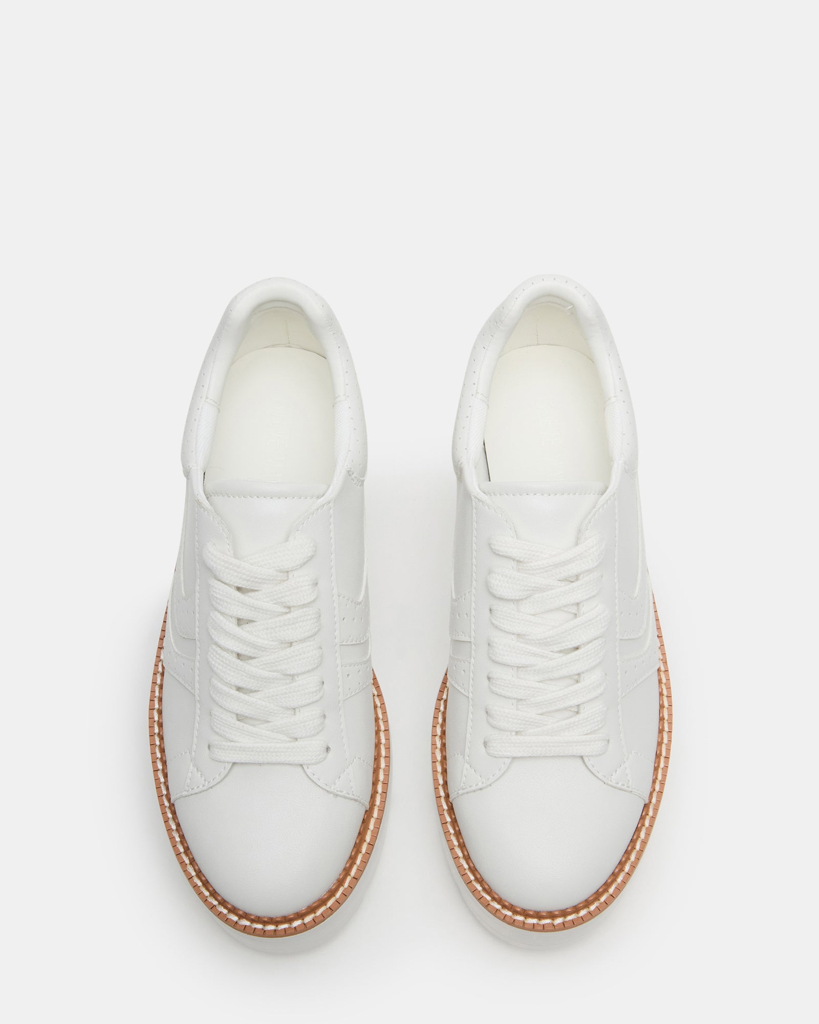 Side view of chunky platform shoes in white vegan leather on sidewalk setting.