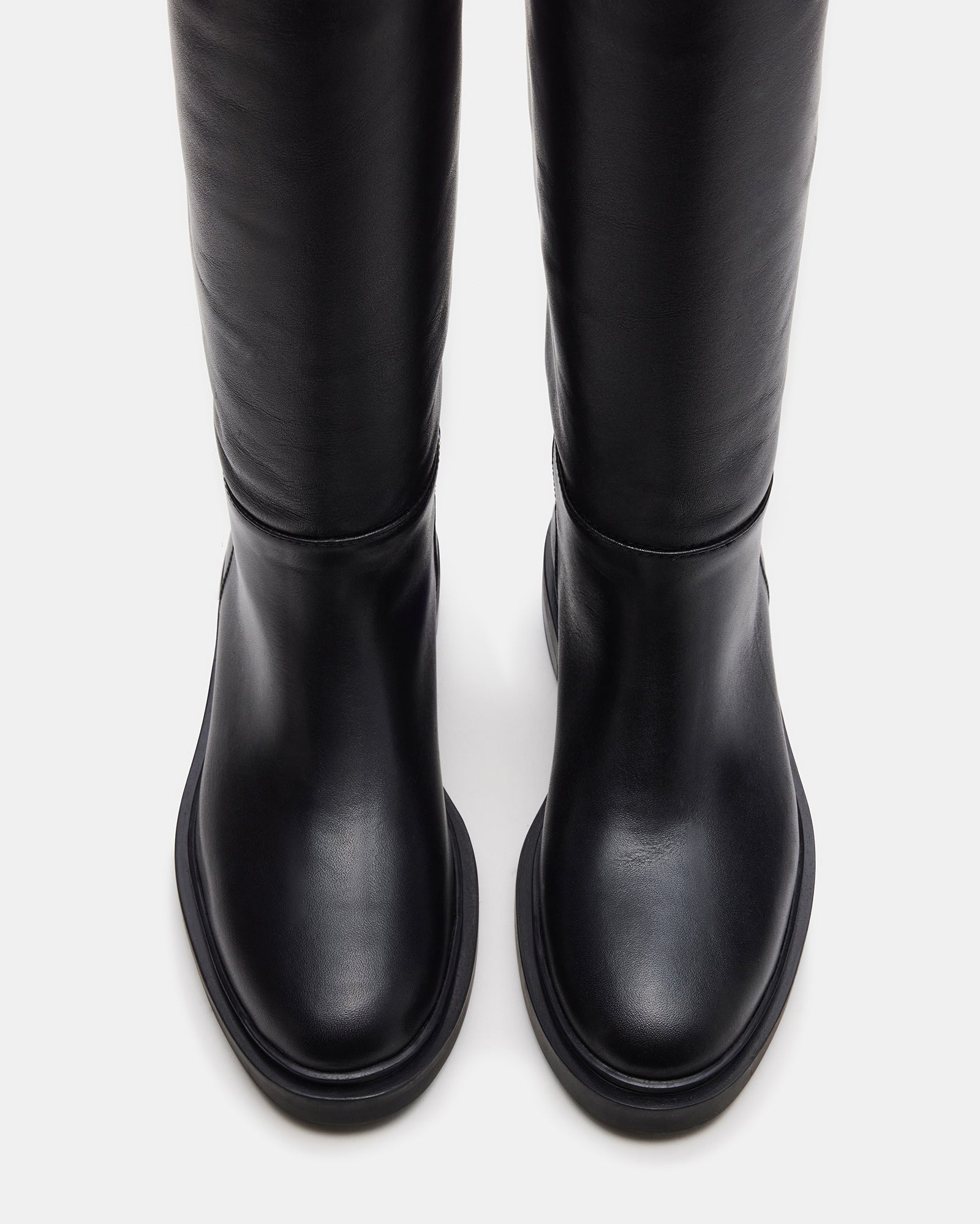 Black leather knee high boots styled with skinny jeans, showcasing versatility.