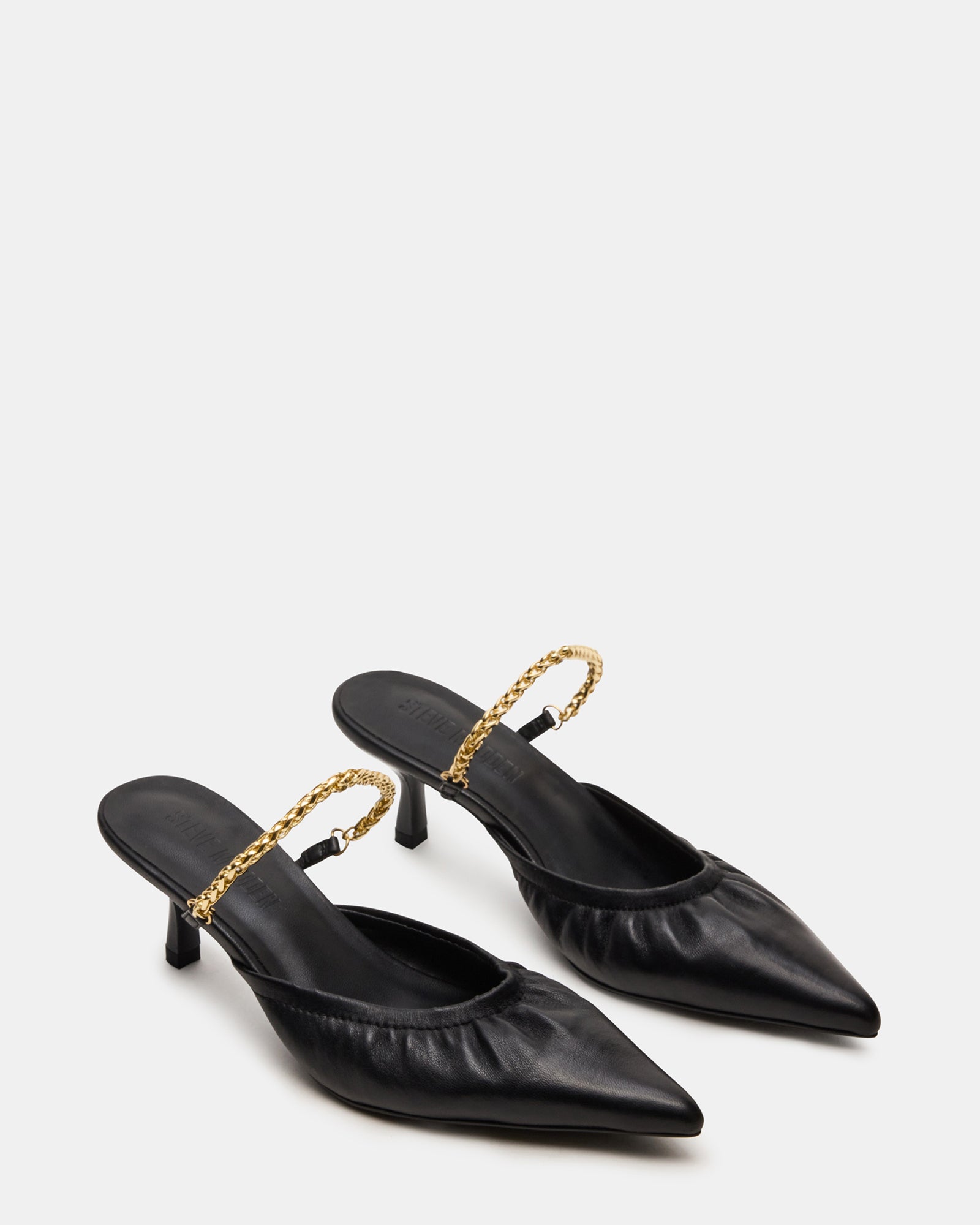 Close-up of the luxurious leather upper of black kitten heel mules.