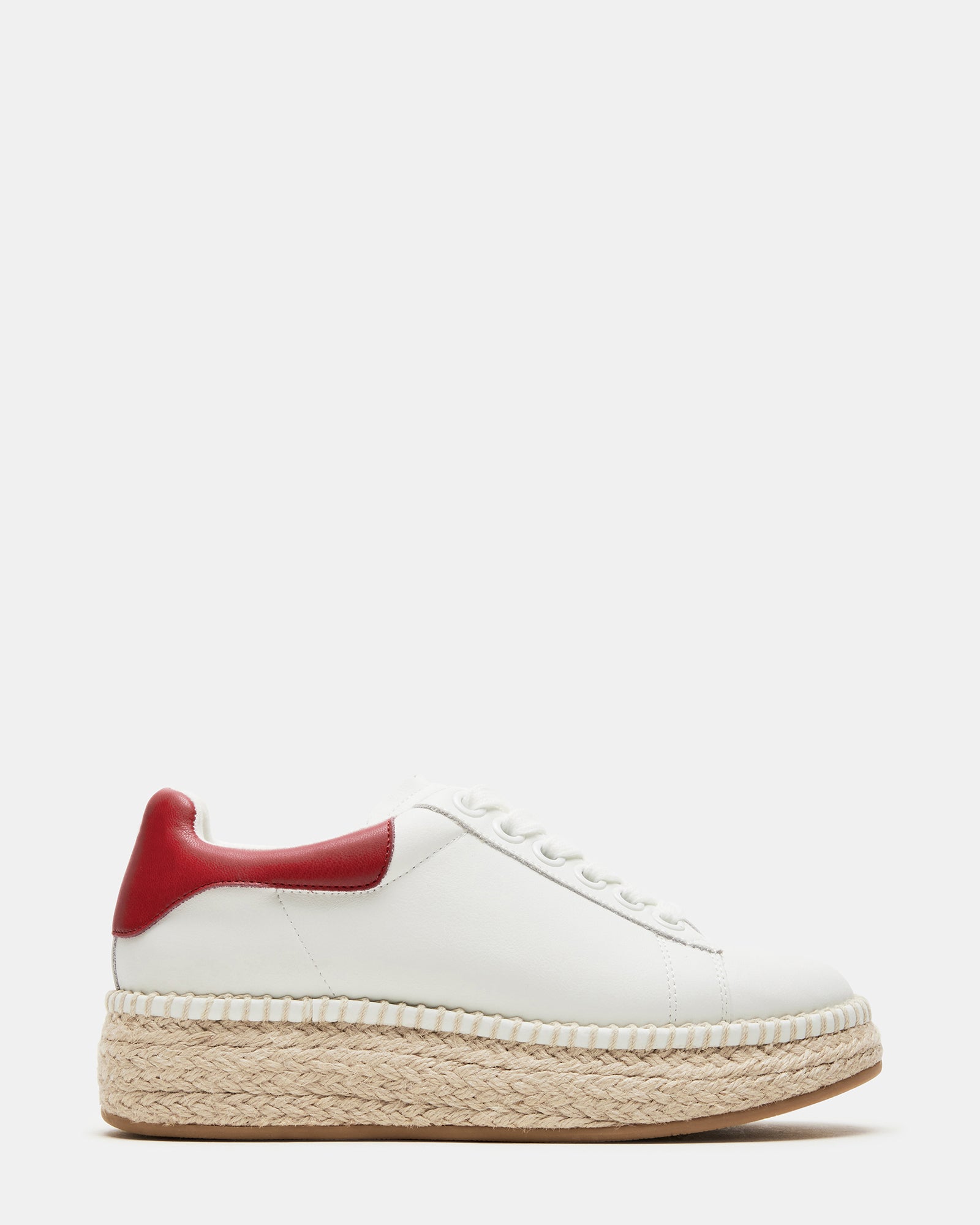 Overhead shot of brown leather sneakers with espadrille trim near outdoor café patio.