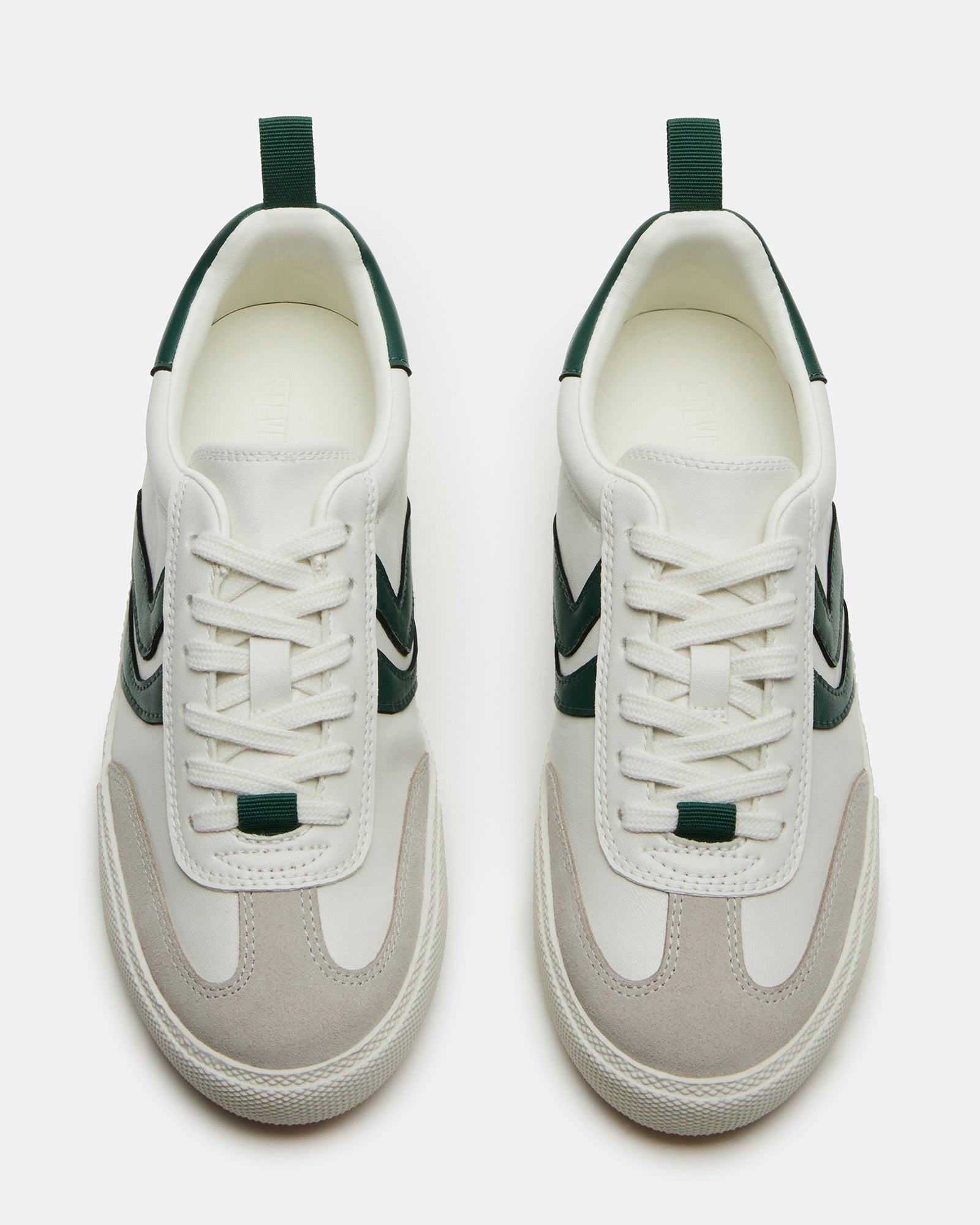 Side view of green low-top shoes on concrete, styled with casual jeans