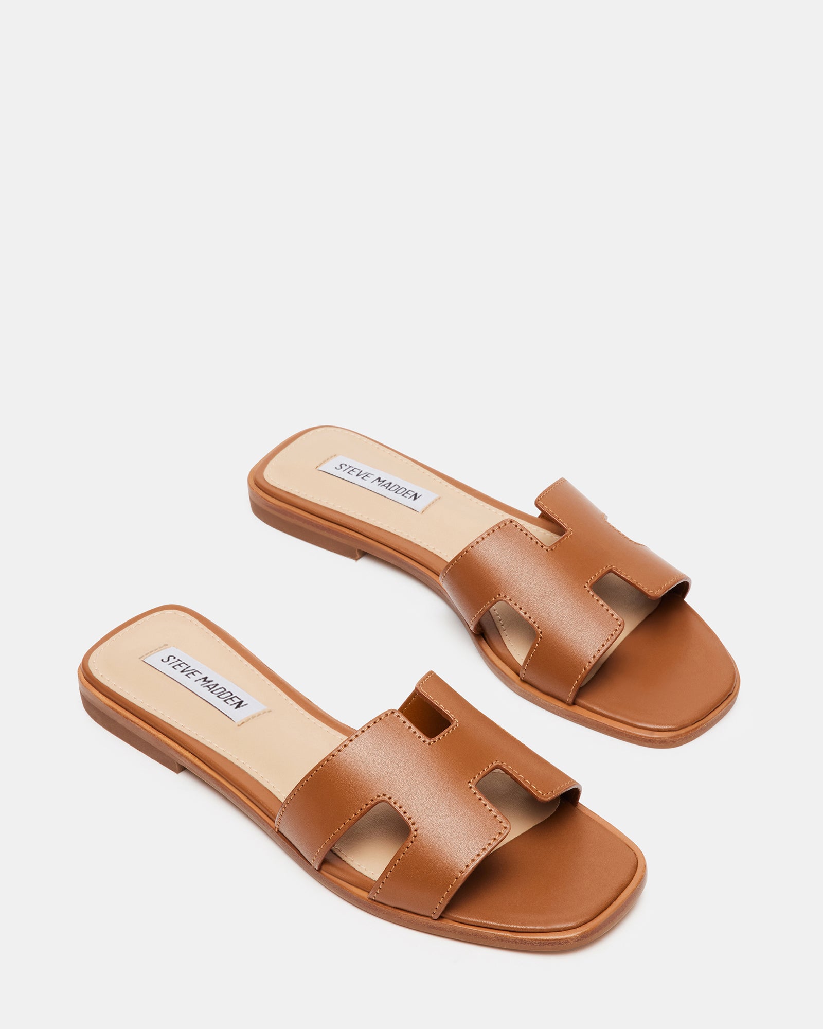 Lifestyle image of womens leather sandals worn with linen pants near the beach.
